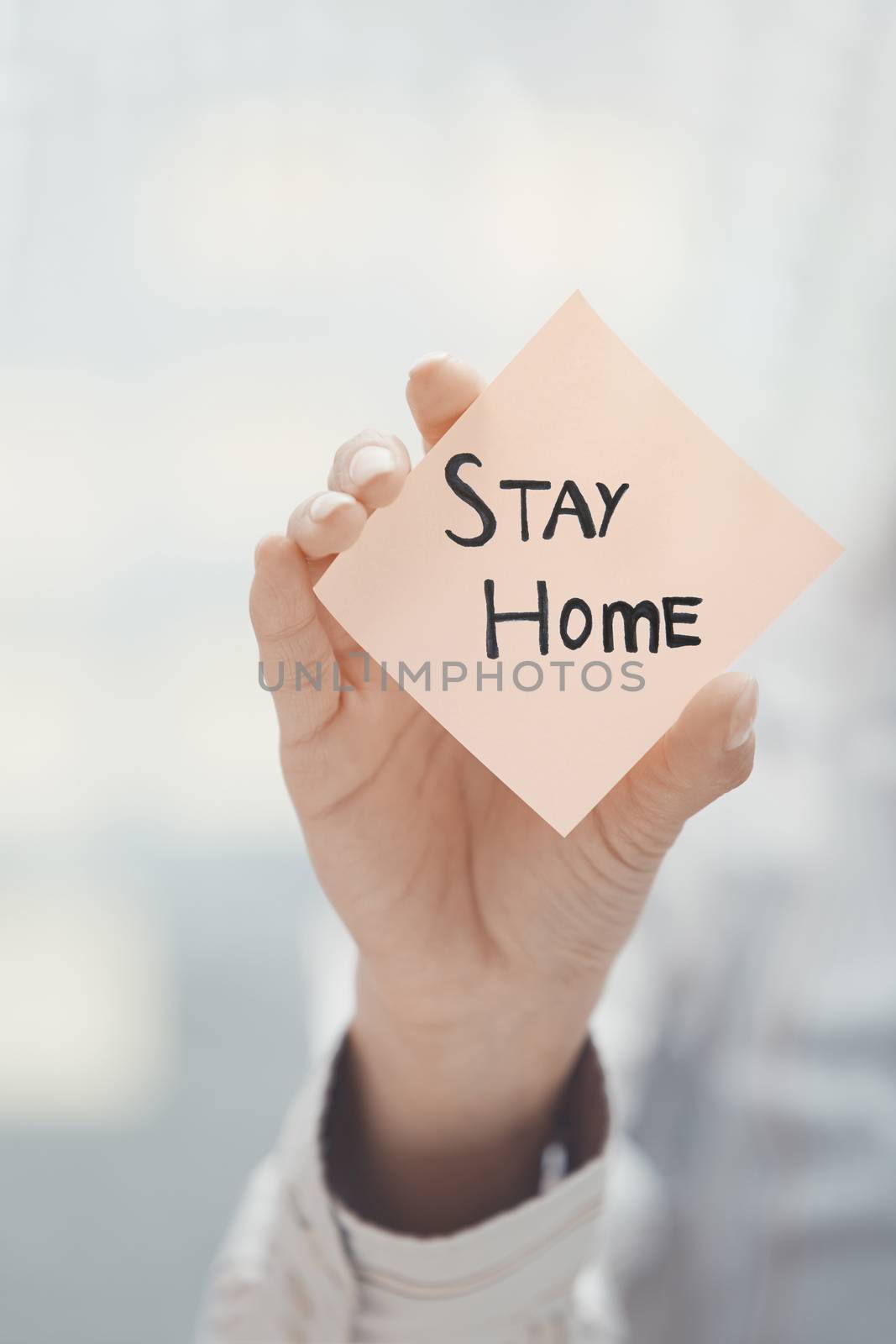 Hand holding sticky note with Stay Home text