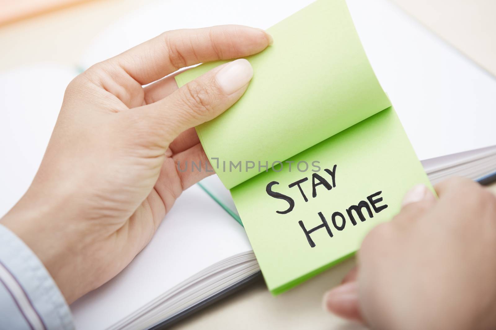 Hands holding sticky note with Stay Home text