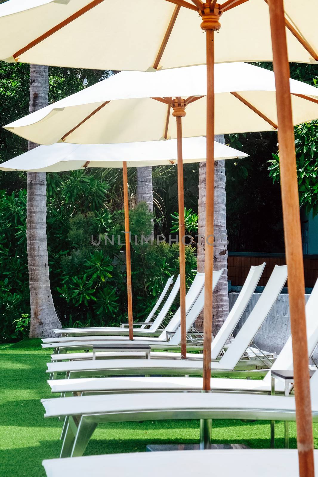Image of Chaise longue at the pool in tropical resort by ponsulak