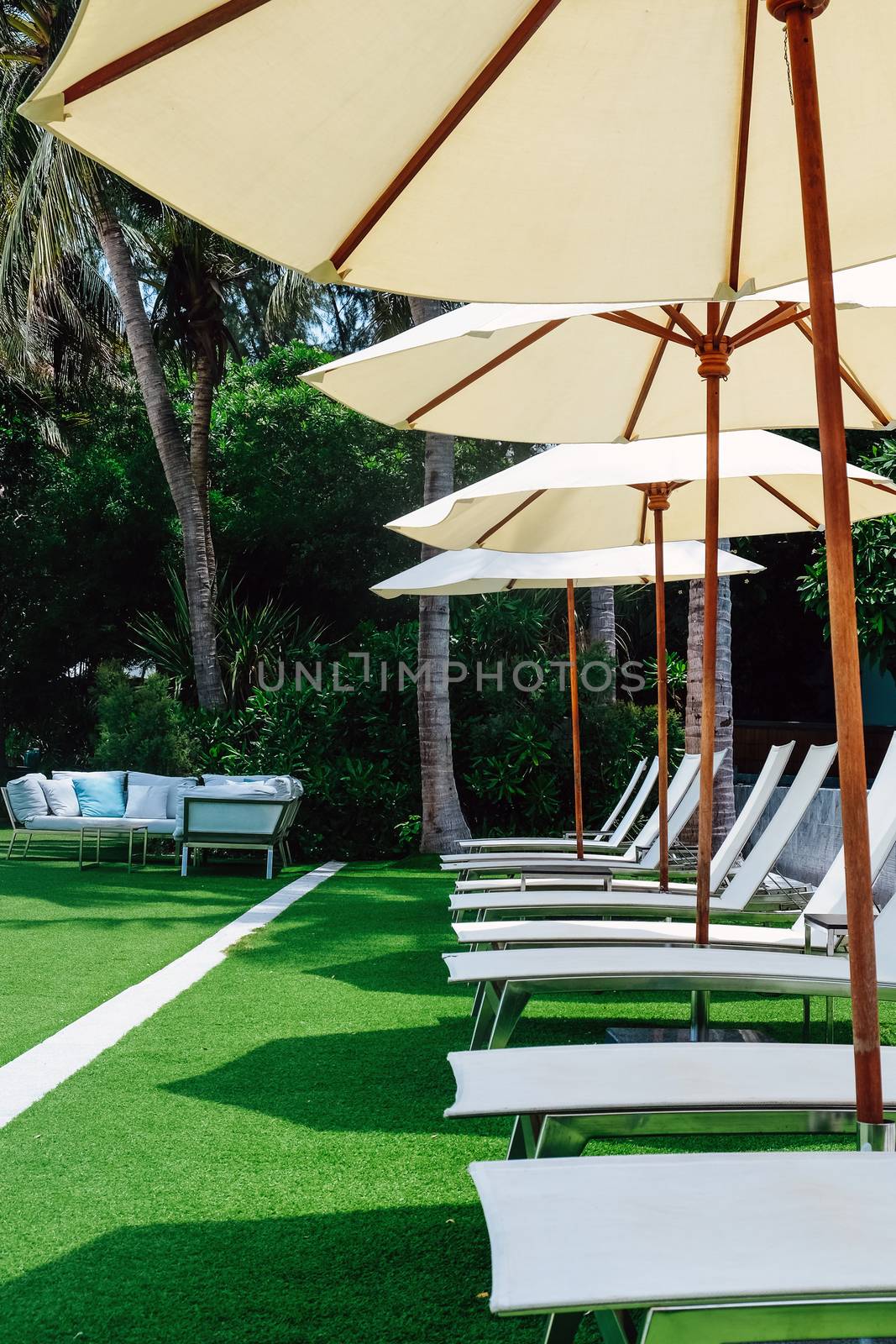 Image of Chaise longue at the pool in tropical resort by ponsulak