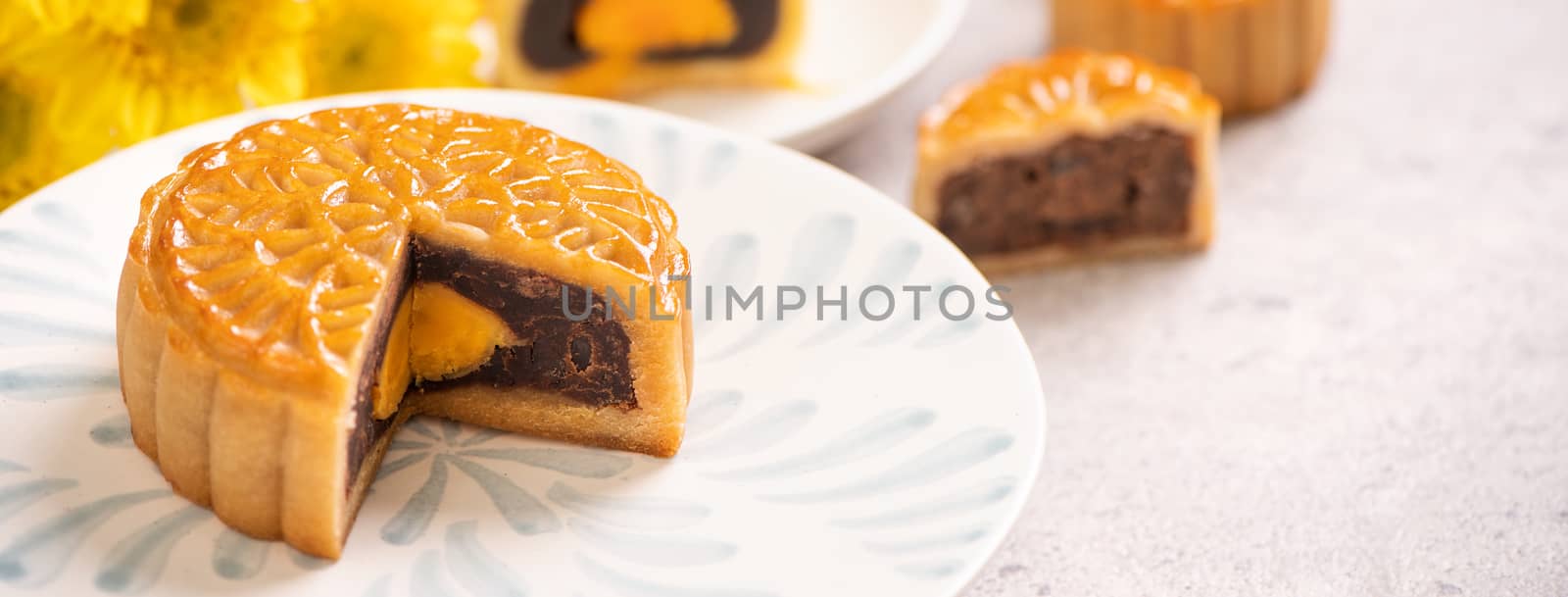 Tasty baked egg yolk pastry moon cake for Mid-Autumn Festival on bright cement table background. Chinese traditional food concept, close up, copy space.