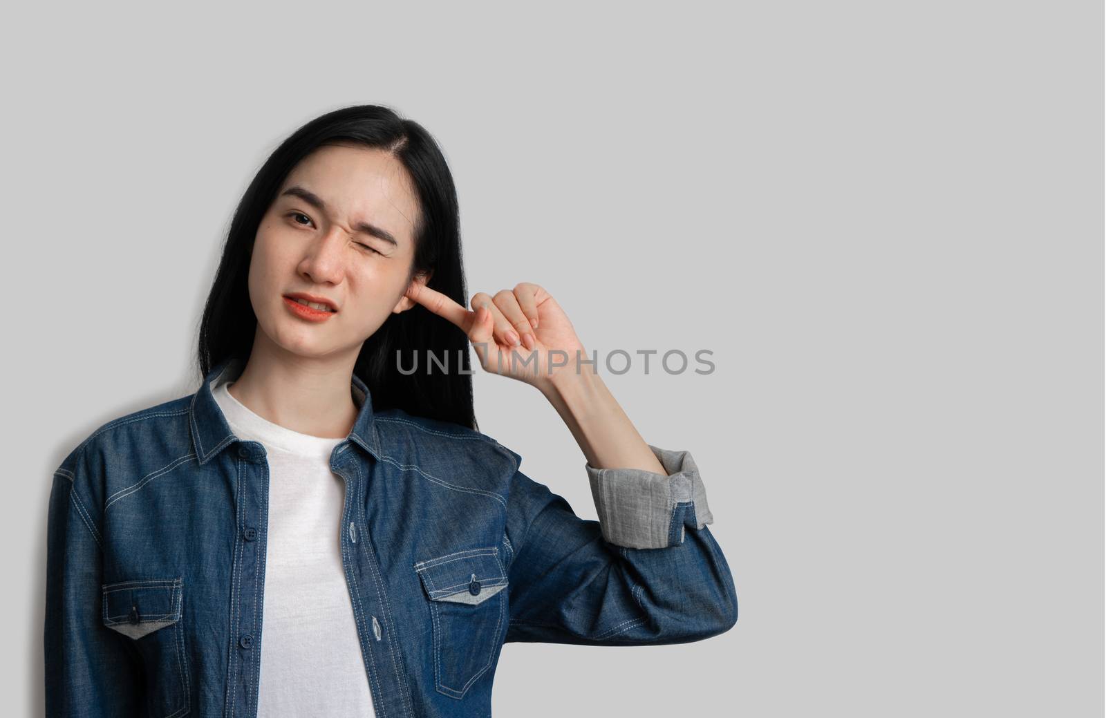 Woman closed her ears not to listen on gray background