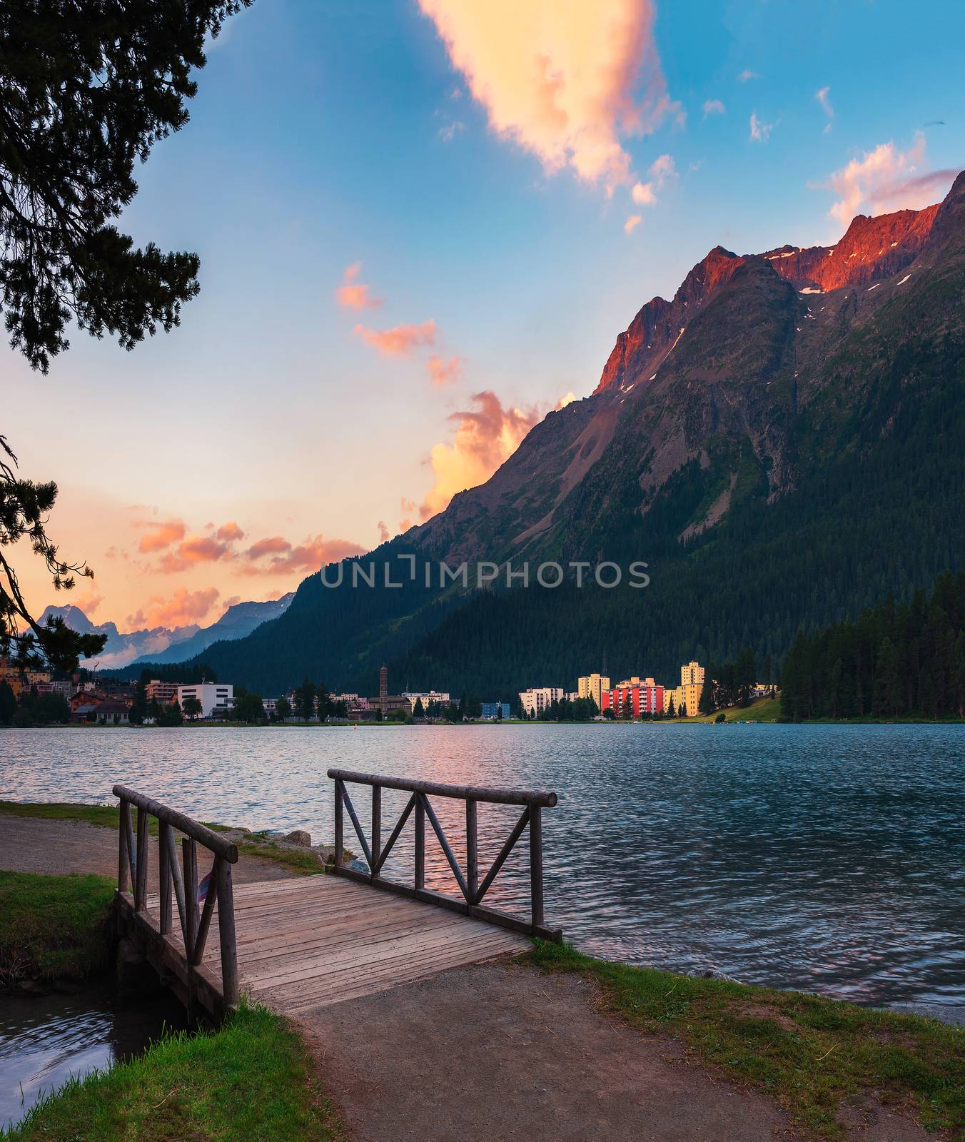 Sunset above St. Moritz with lake also called St. Moritzsee, a wooden footbridge in the foreground and Swiss Alps in the background in Engadin, Switzerland.