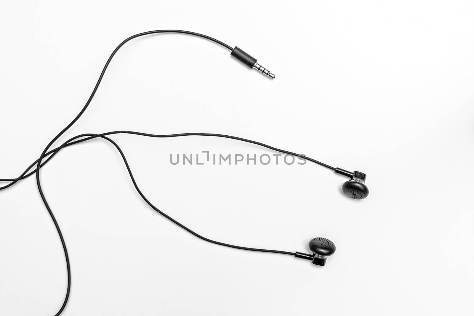 Small black headphones on a light background with tangled long wires