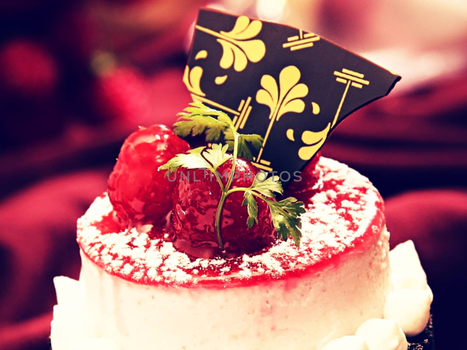 Soft focus of a cake topped with re berries and chocolate.