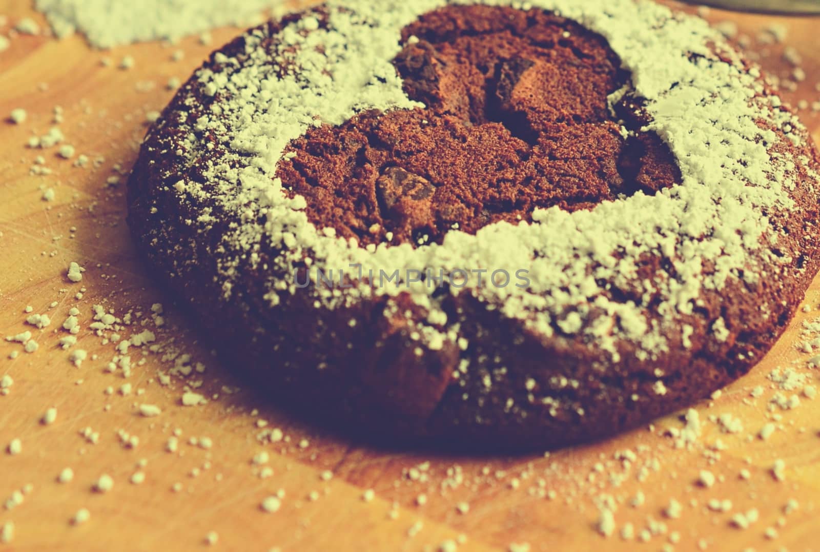 Closeup of a chocolate cookie with a heart design on a wooden board.