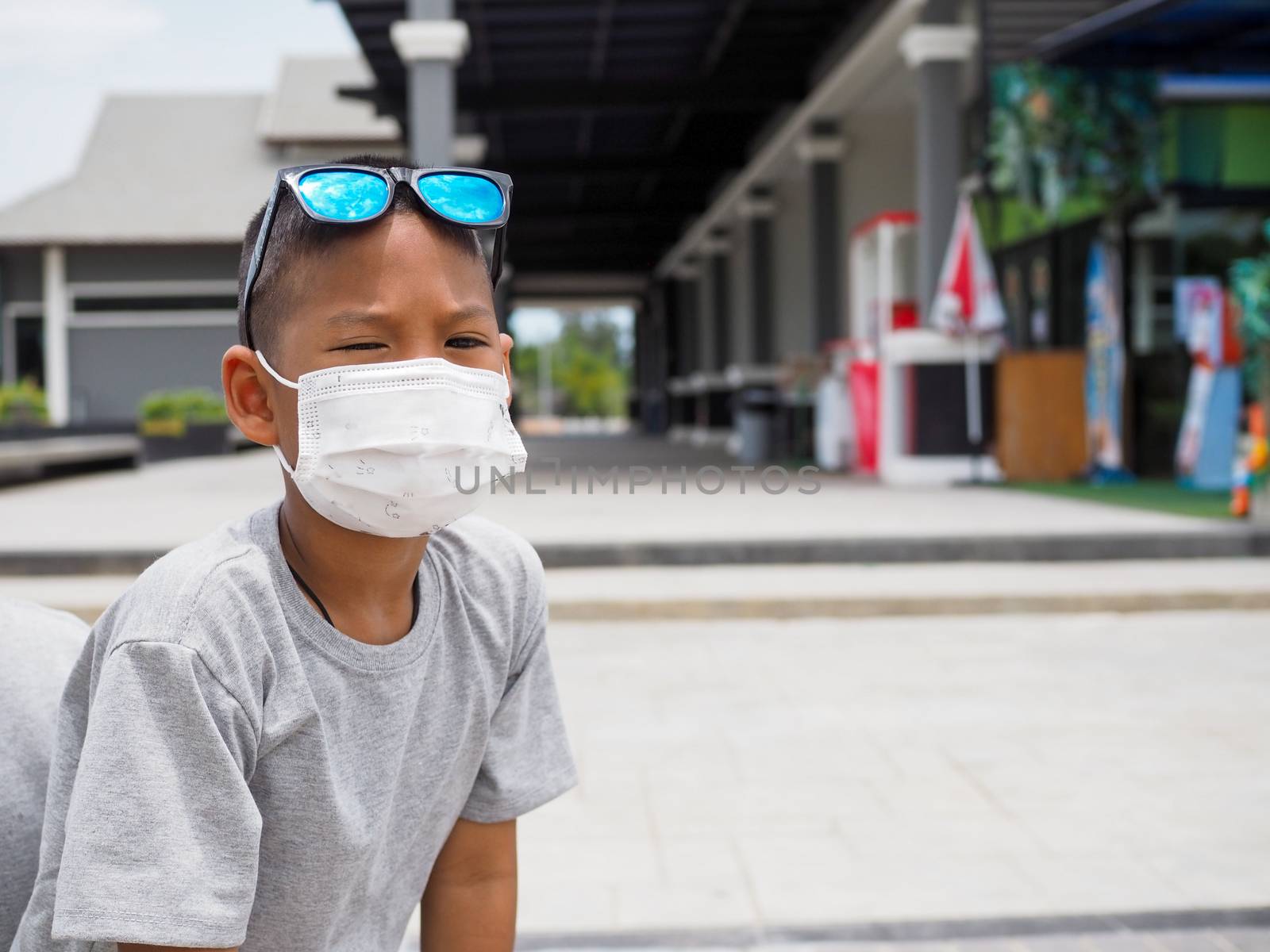 A boy sitting with a protective mask He sat and looked at the ca by Unimages2527