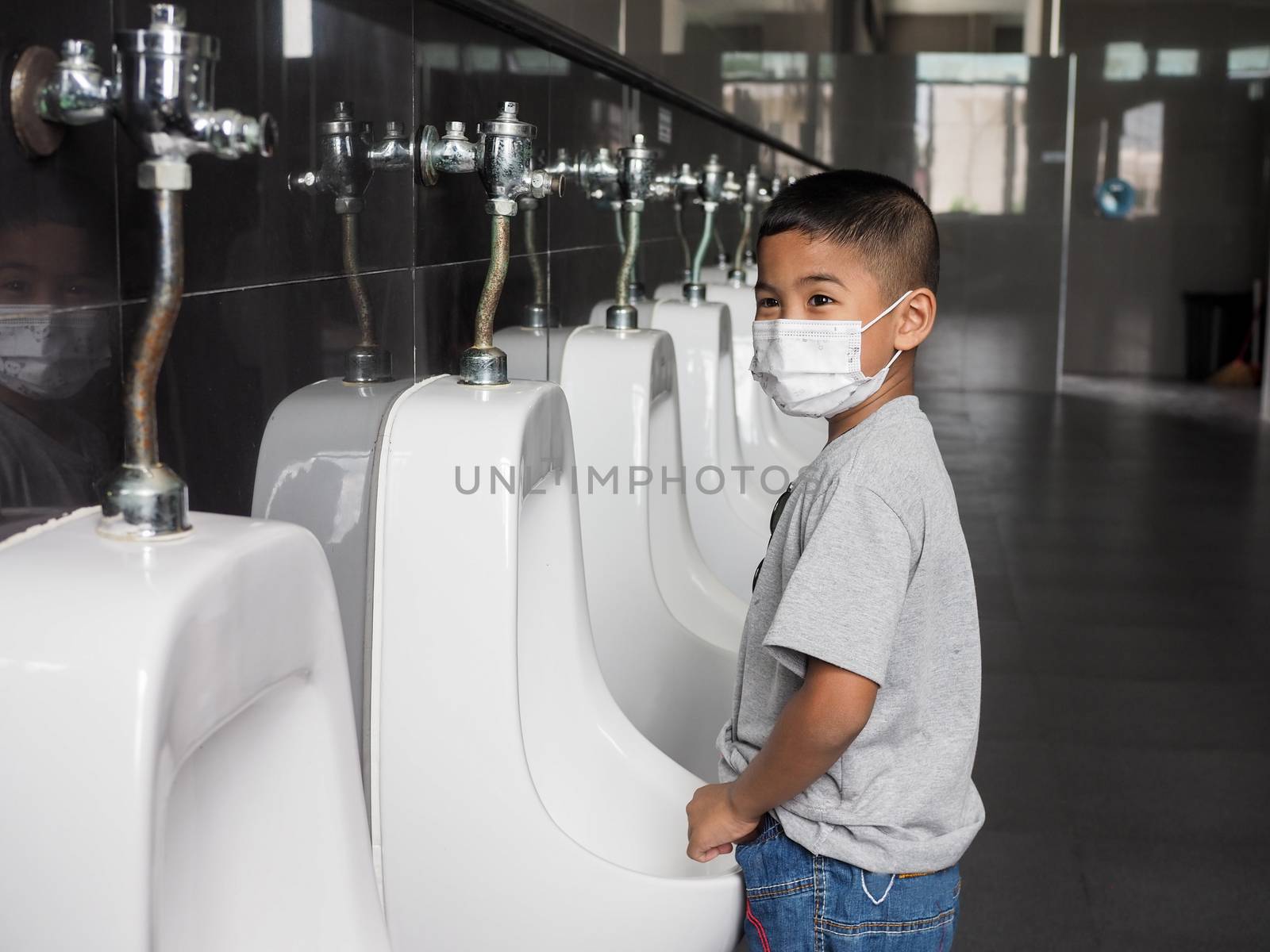 Boy wearing a protective face He is urinating in the public toilet.