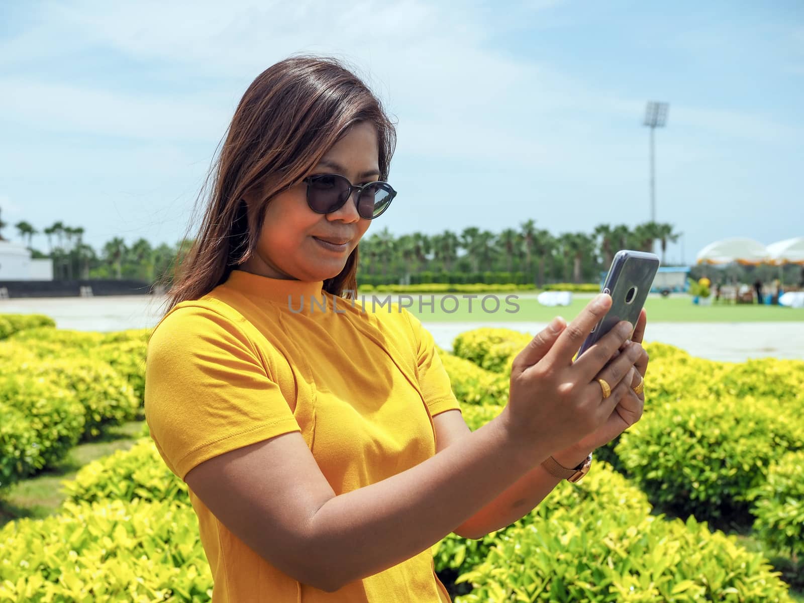 Asian women wearing yellow mats and eyeglasses. Stand selfies in attractions Happily.