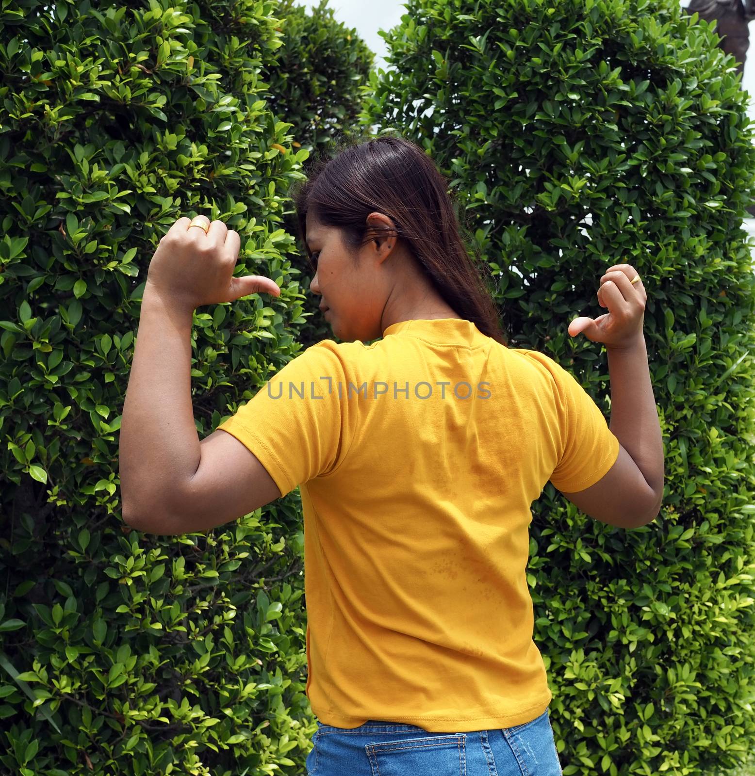 Asian woman Wearing a yellow shirt With a finger pointing at the back of himself.