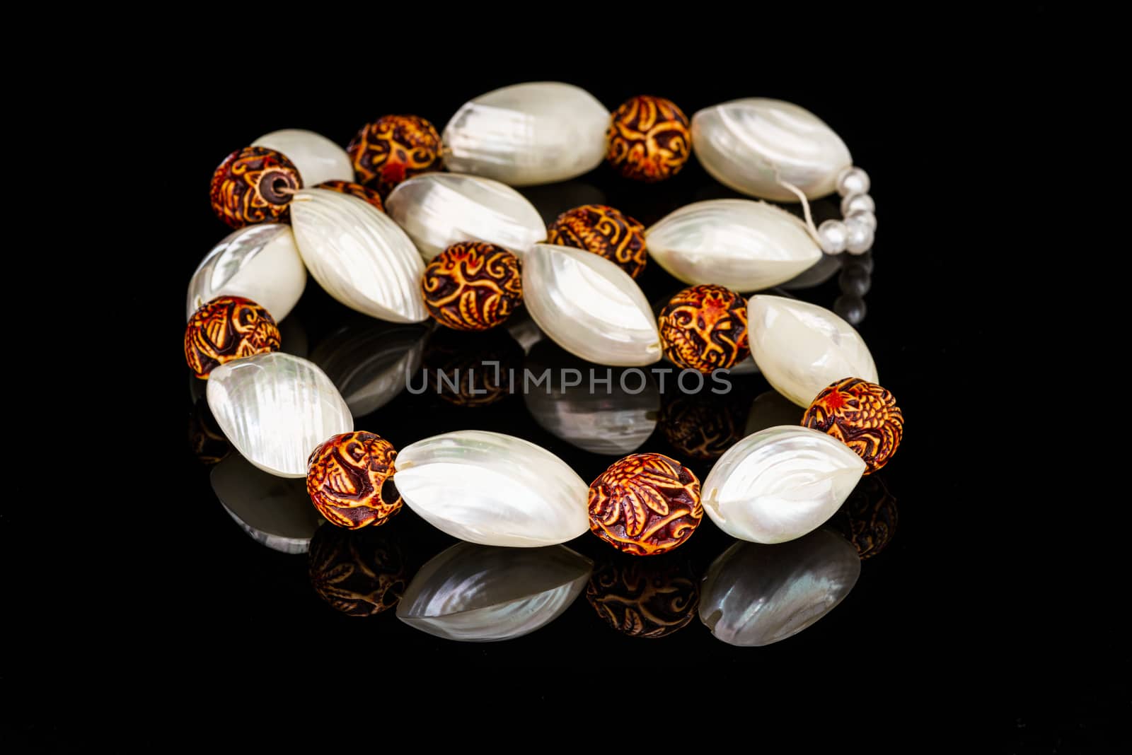 White pearl shell necklace on a black reflective background