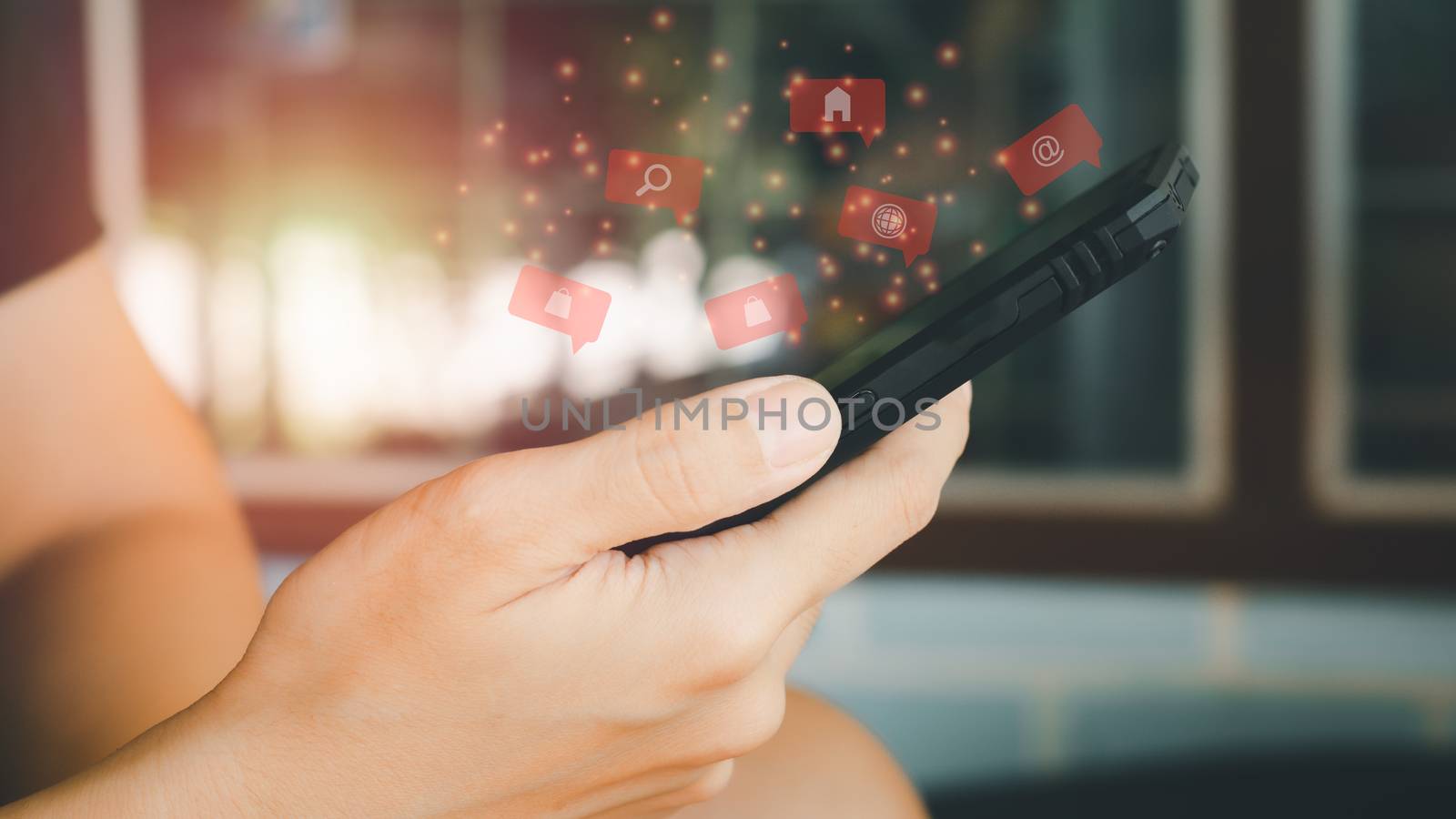 Social media with smartphone concept. Hand holding black mobile phone with red icon of applications, internet marketing, e-learning, and shopping online.