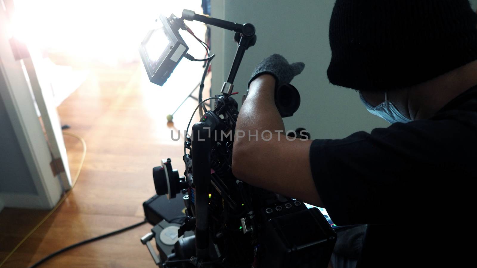 Behind the scenes of photographer shooting video or movie production with camera set on tripod at location.