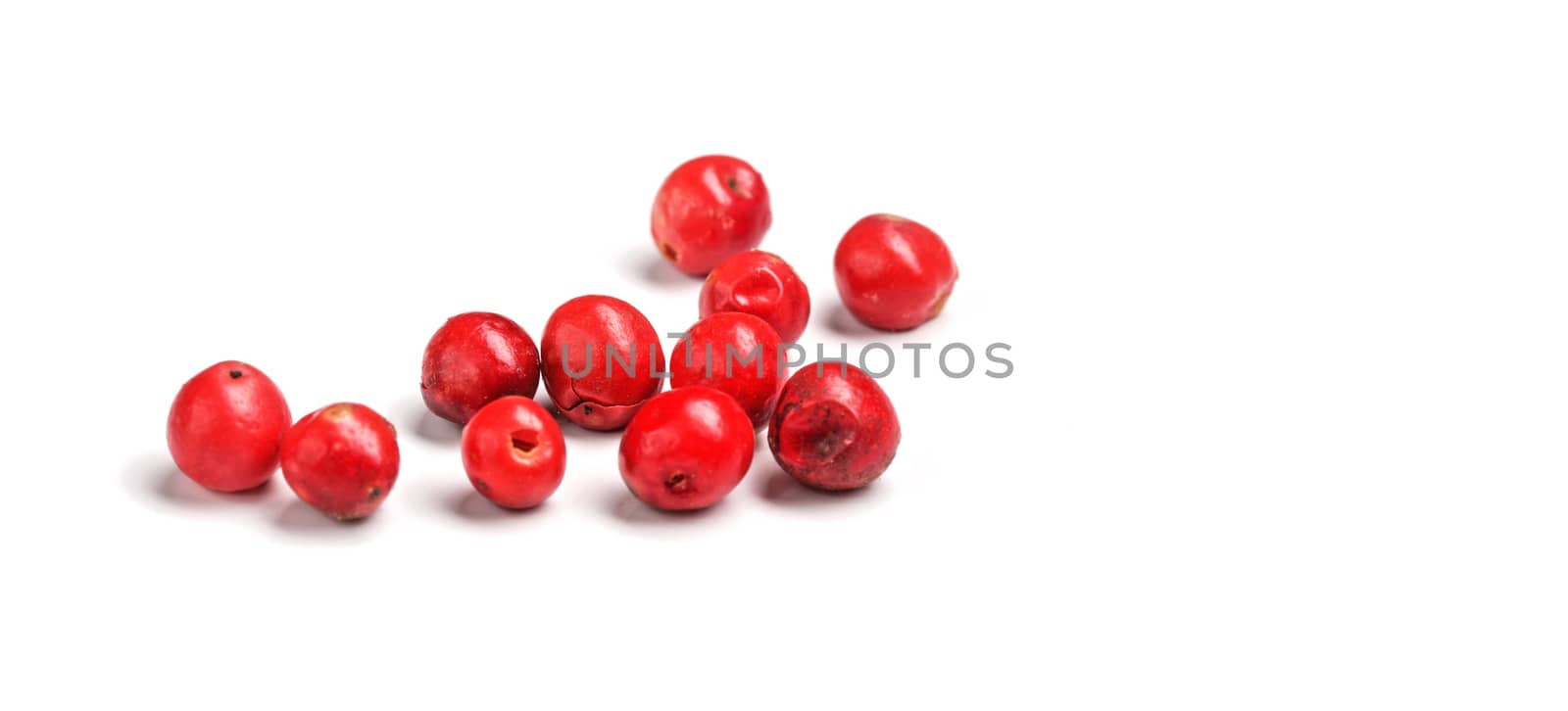 Red or pink peppercorns on board, closeup photo isolated with white background.