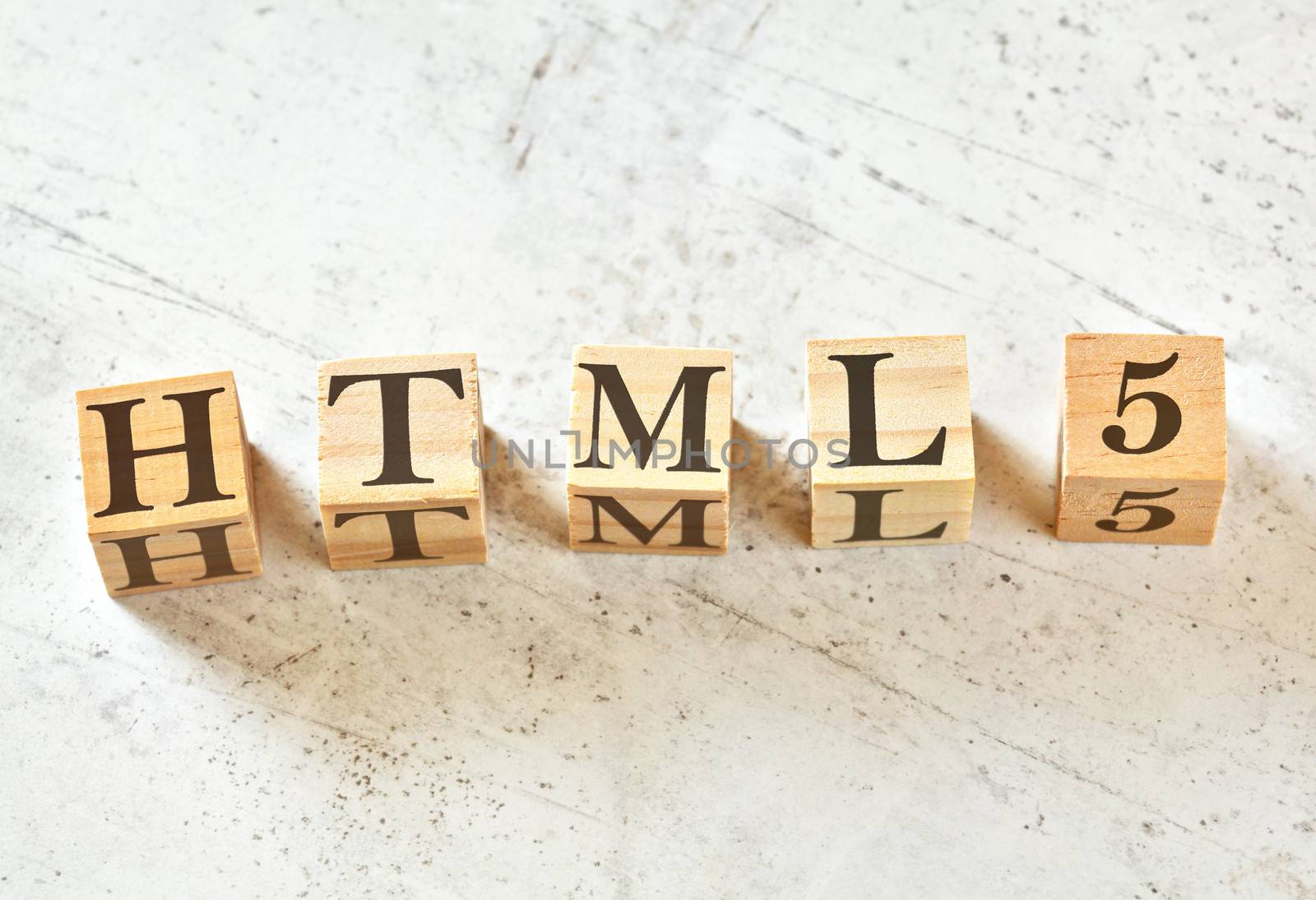 Five wooden cubes with word HTML5 on white stone like board, view from above.