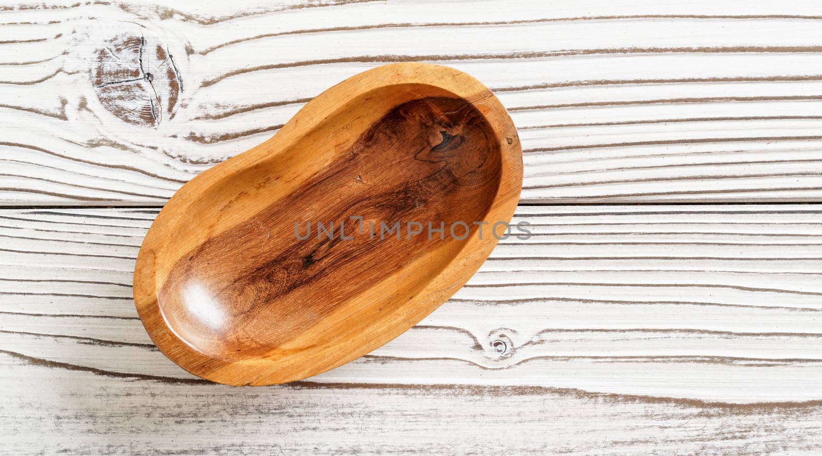 Small polished rosewood bowl on white boards desk, closeup view from above.