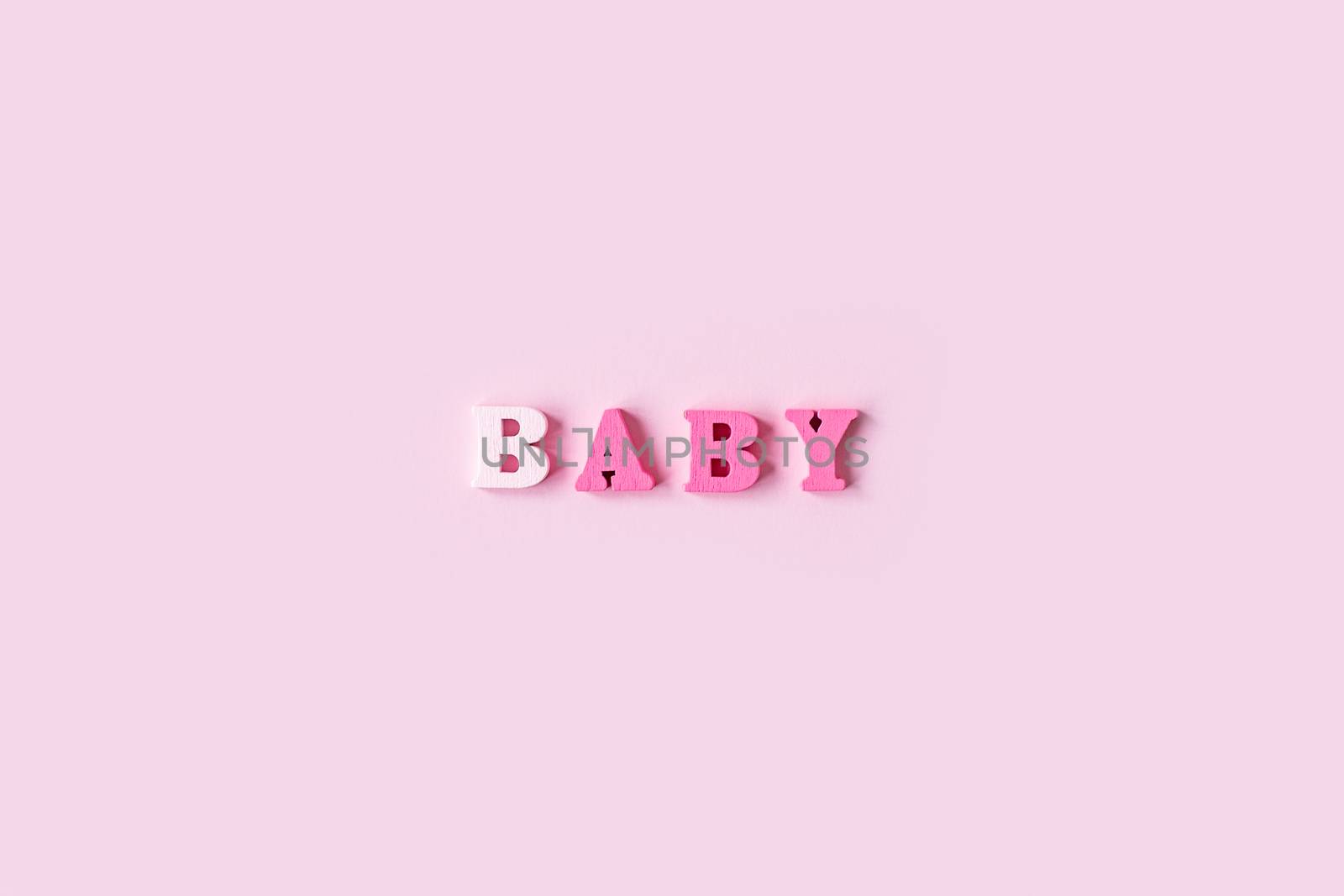 The word BABY is made of wooden letters on a pale pink background. Banner design. Baby shower concept. Photo of minimal background with beeautiful decor and place for text isolated pink background by Pirlik
