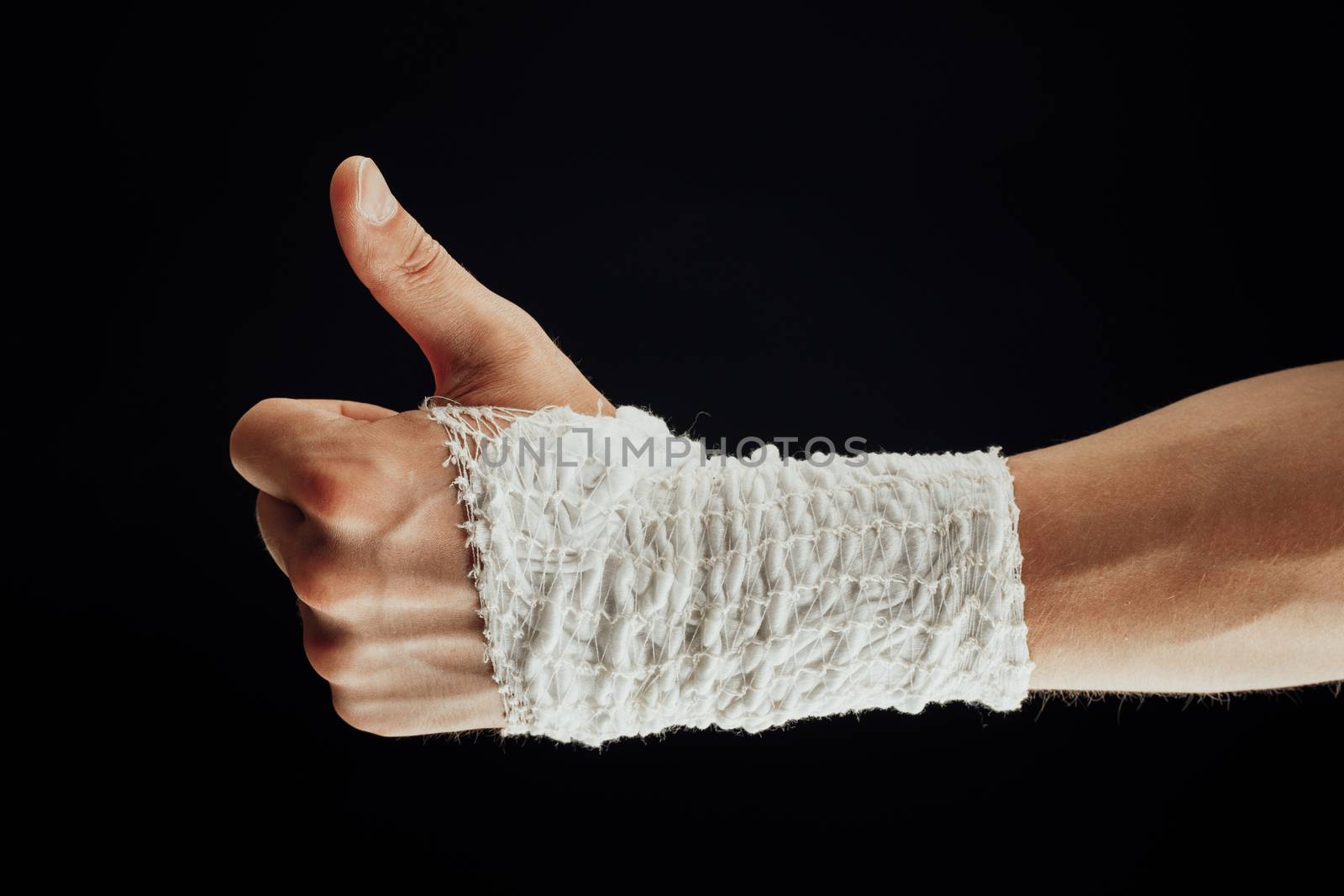 wrist wrapped with healing bandage, thumbs up, isolated on black