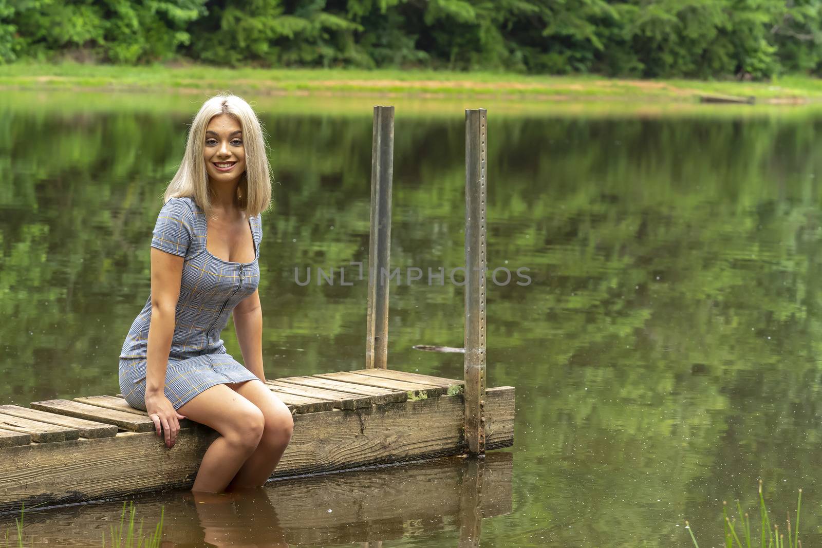 A gorgeous young blonde model poses outdoors in a field of sunflowers while enjoying a summers day