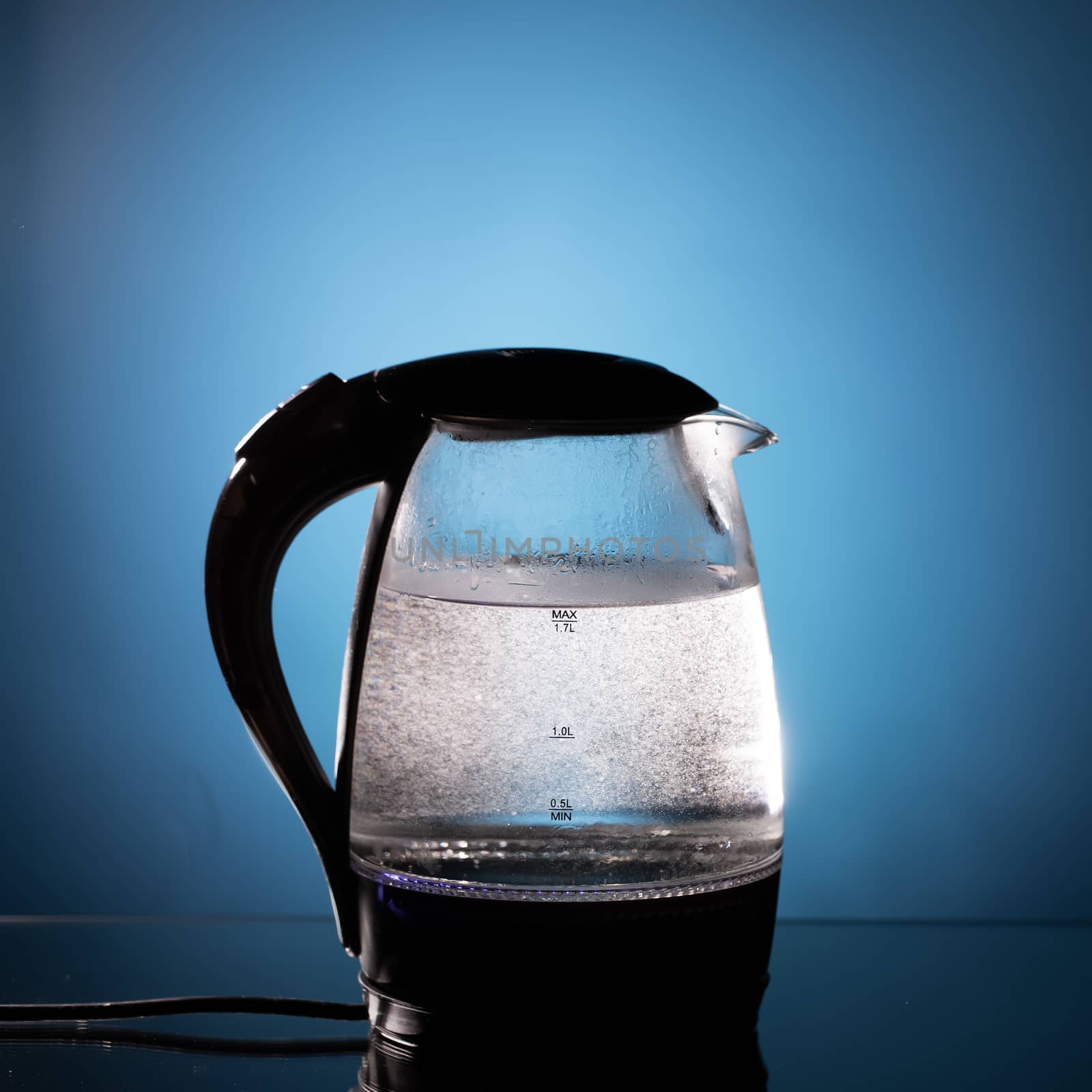 electric glass kettle on blue background