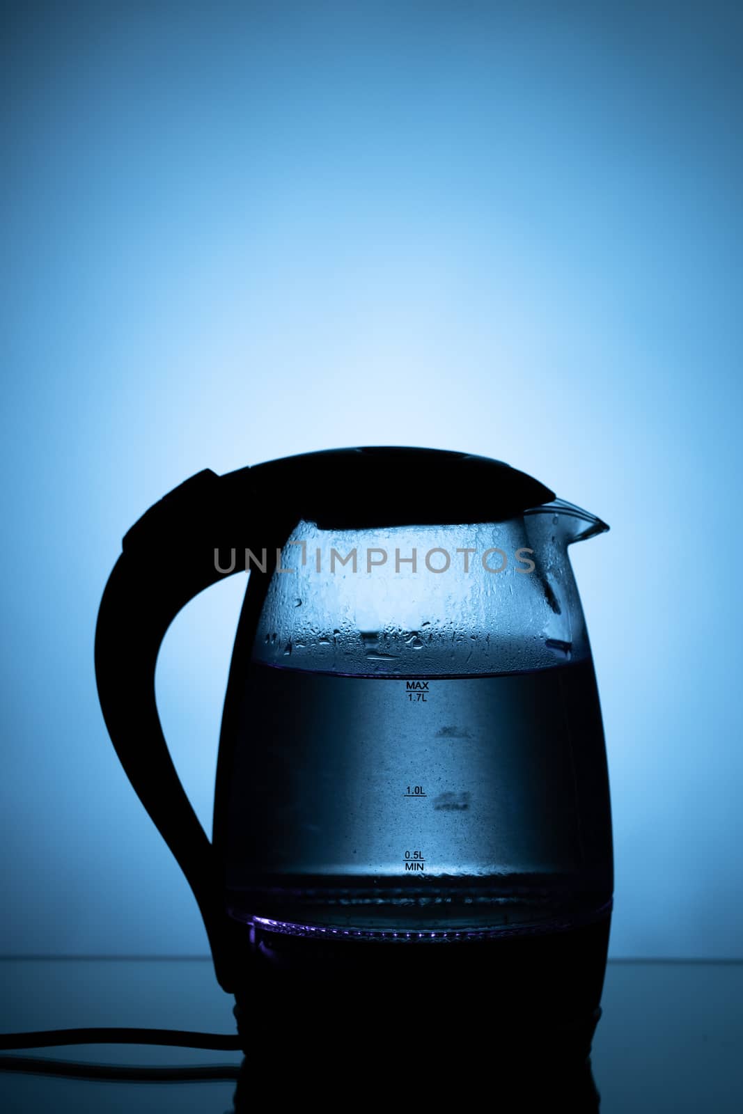 electric glass tea kettle on blue background