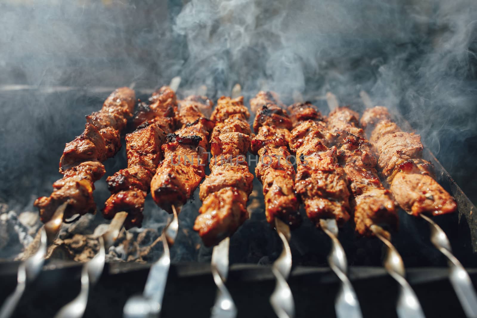 grilled barbecue meat on skewers with smoke by nikkytok