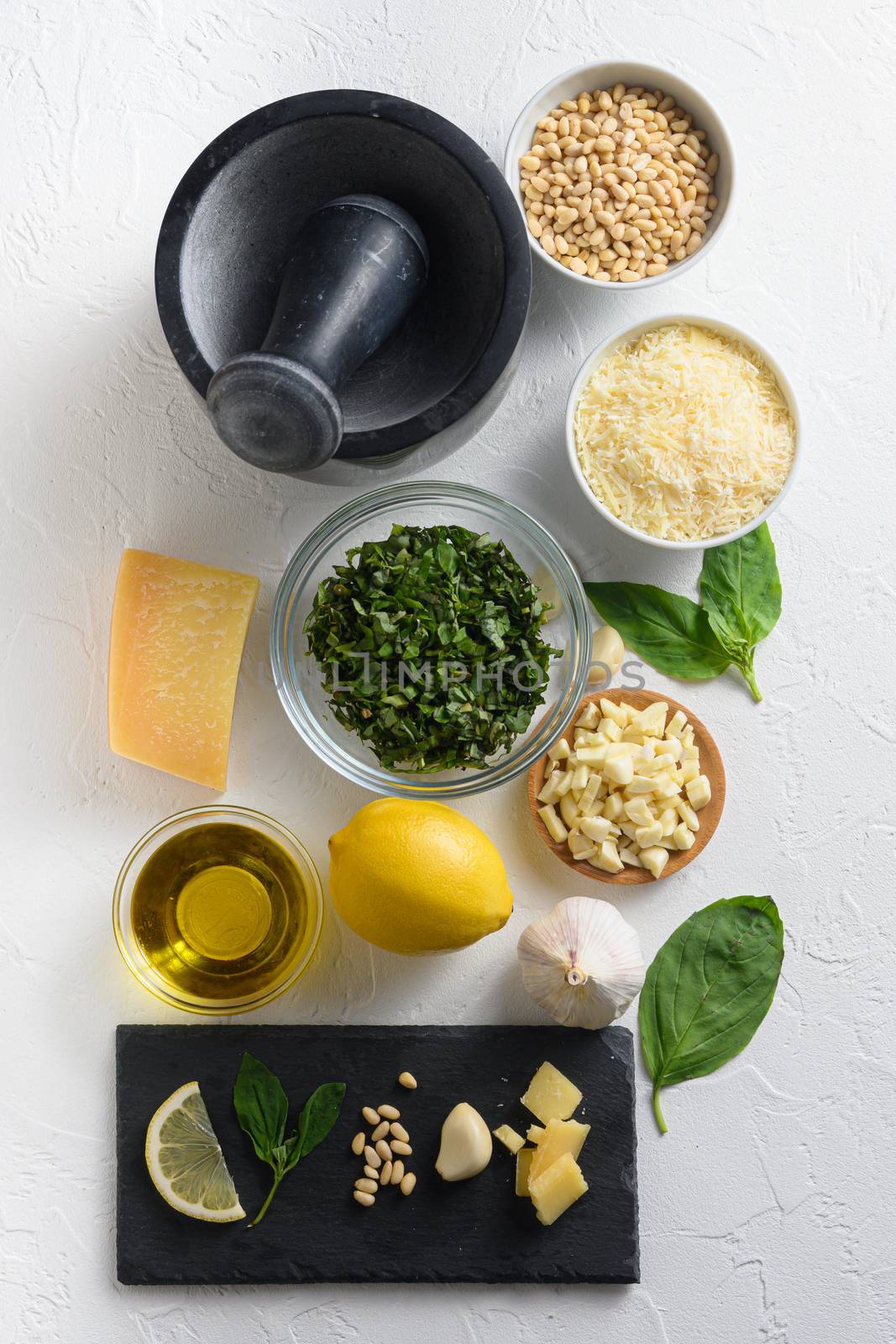 Pesto alla Genovese , Basil Sauce Different ingredients for Italian pesto. Grated parmesan cheese, basil leaves, pine nuts, olive oil, garlic On the white stone slate side top view. by Ilianesolenyi