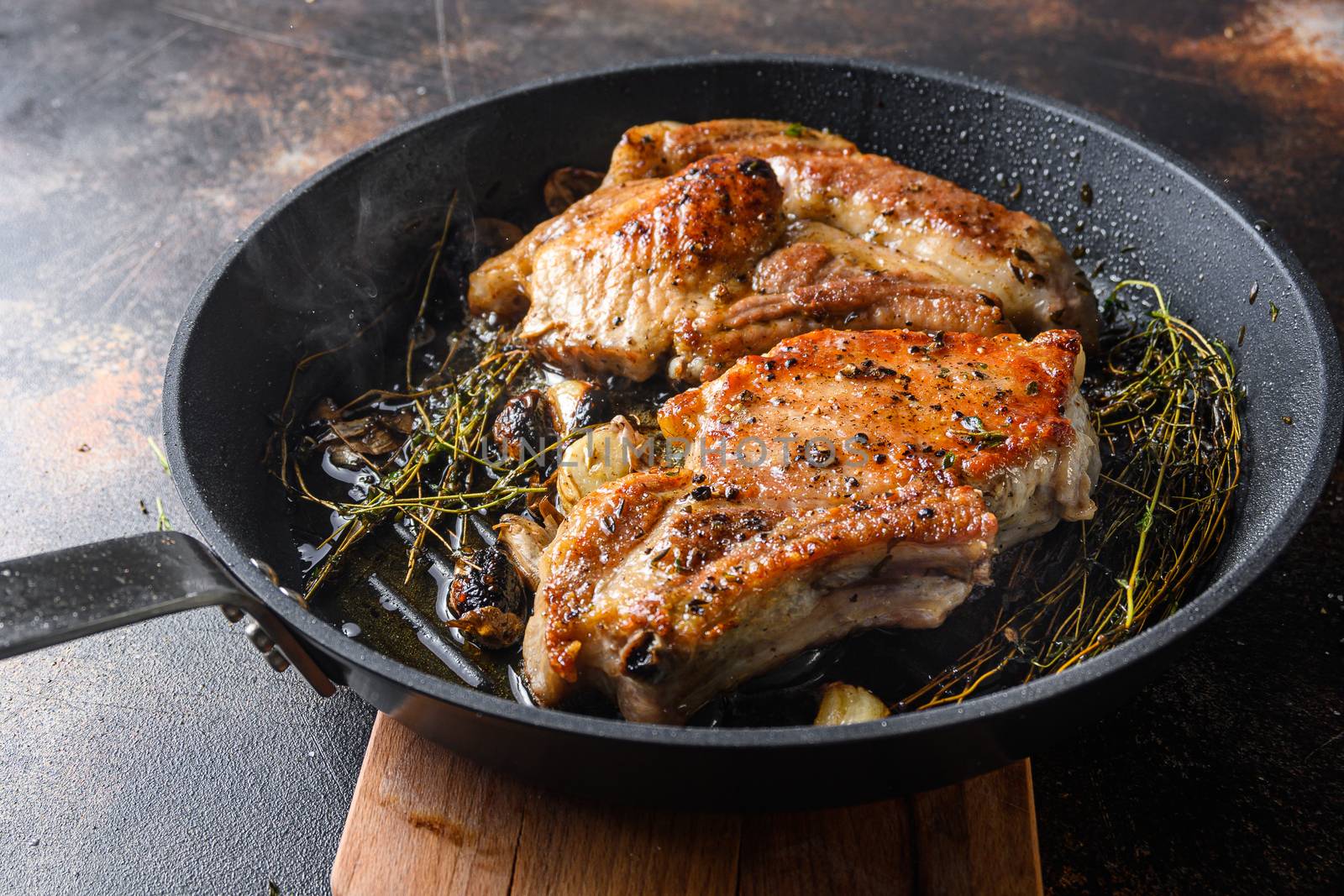 Barbecue Pork Chops on the bone with seasonings and grilled on hot skillet with smoke just from the fire close up side view
