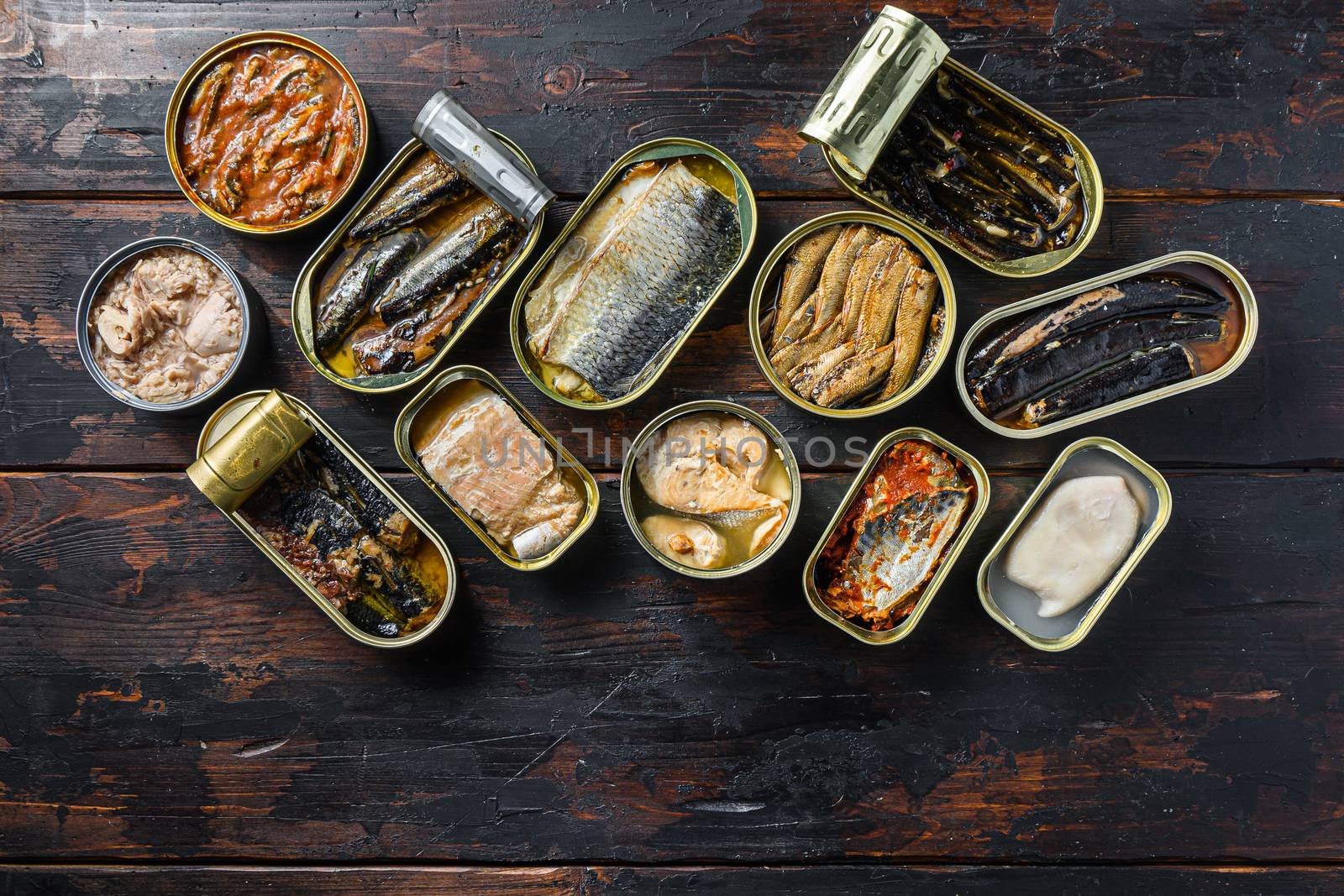opened cans conserve with Saury, mackerel, sprats, sardines, pilchard, squid, tuna over wood table top view.