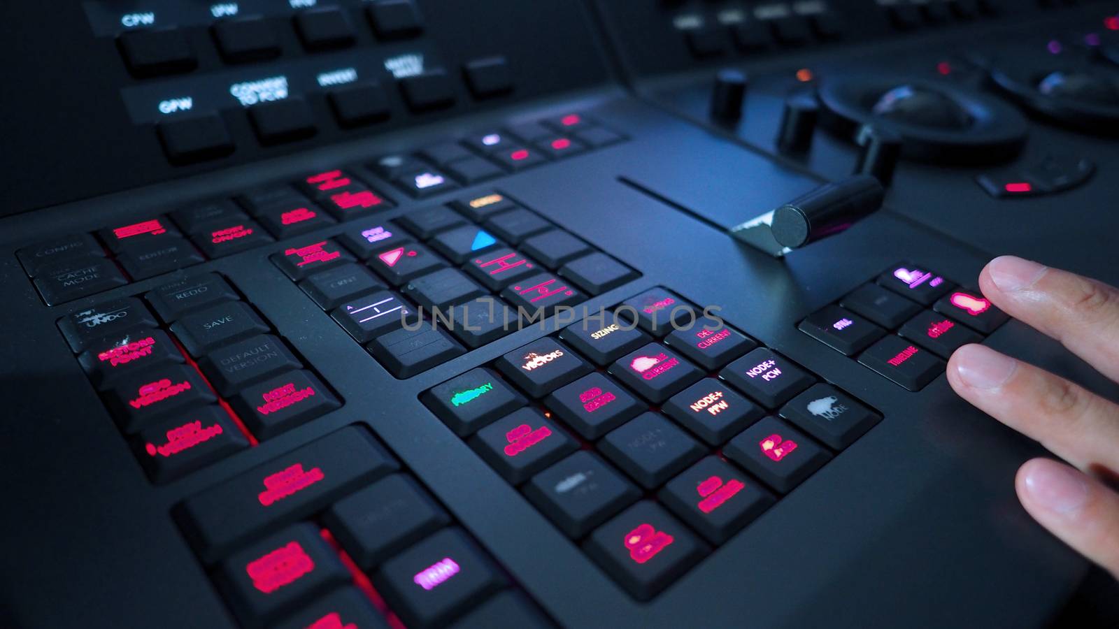 Telecine controller machine and man hand editing or adjusting color on digital video movie or film in the post production stage. 