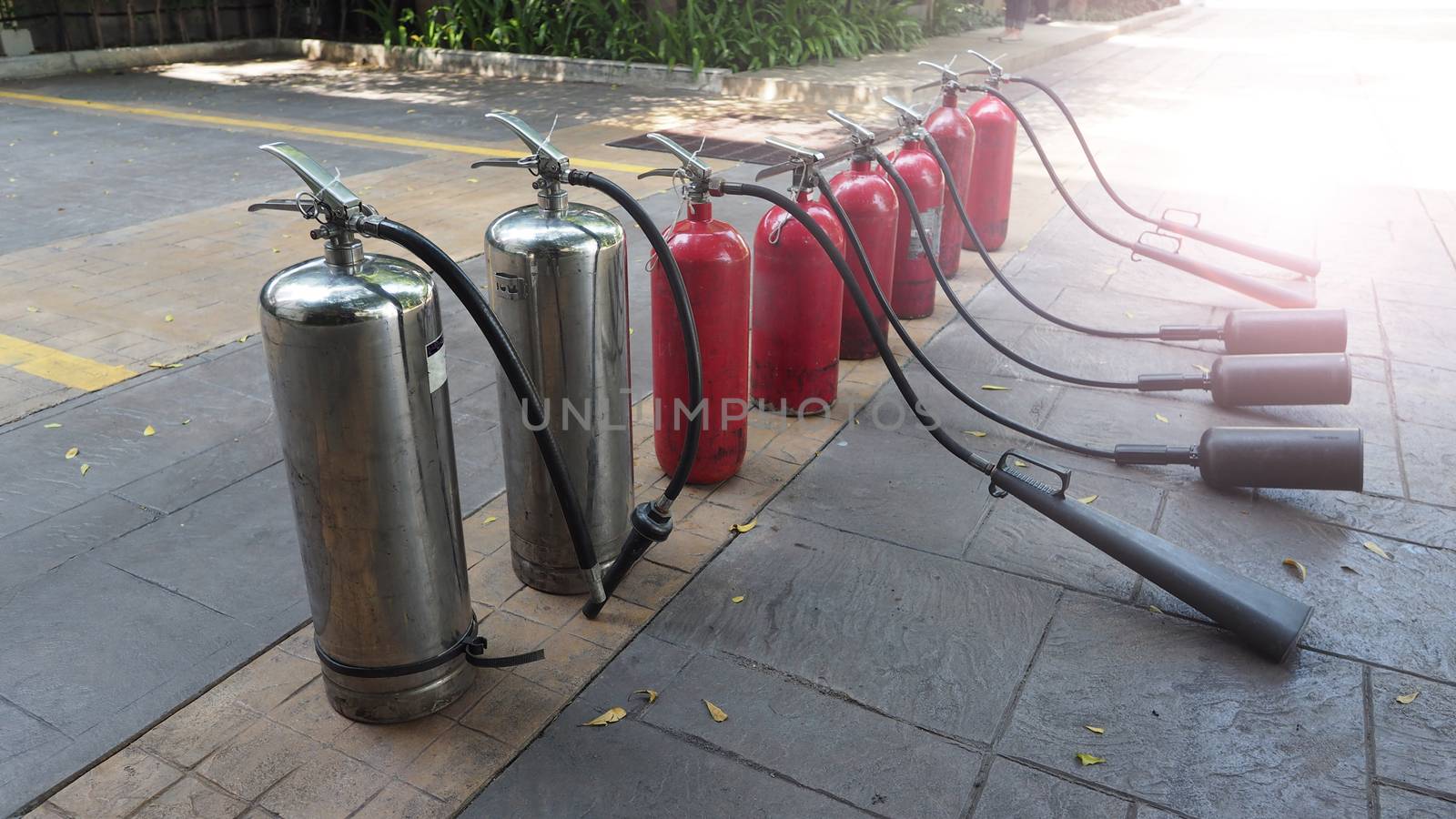 Red and silver color of fire extinguisher tank prepaired on the floor for emergency case.