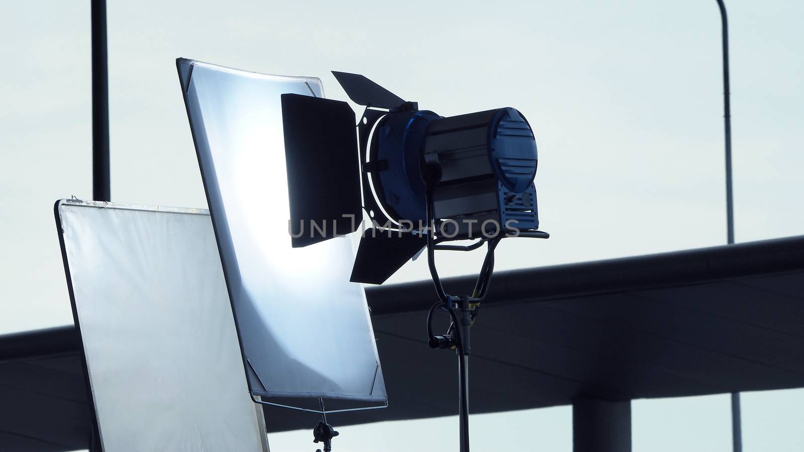 Big LED spotlight and tripod equipment for video or movie production at outdoor location.