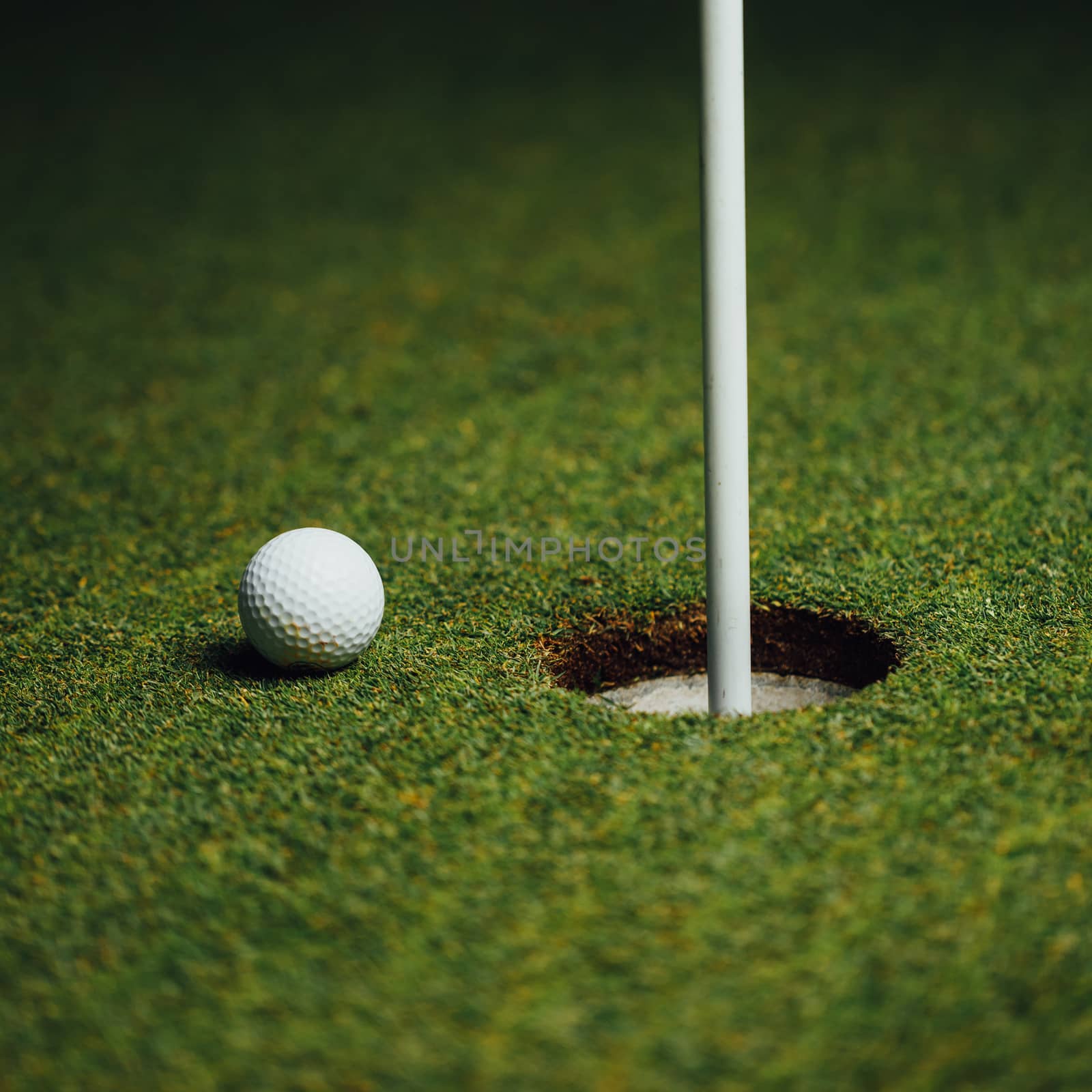 golf ball nearby hole with pin flag, green grass background, closeup view by nikkytok