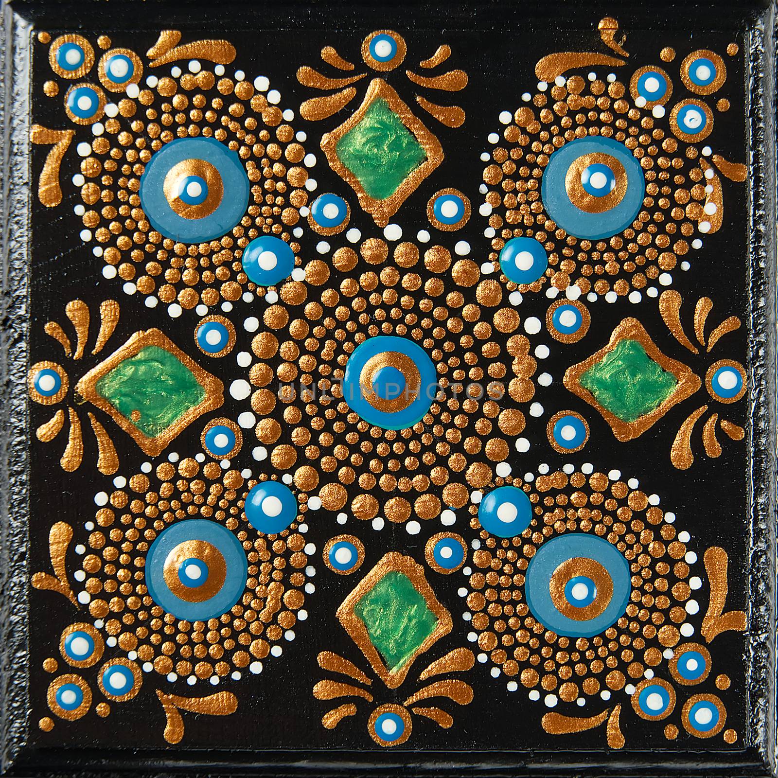 Mandala dot art painting on wood tiles. Beautiful mandala hand painted by colorful dots on black wood. National patterns with acrylic paints, handwork, dot painting. Abstract dotted background