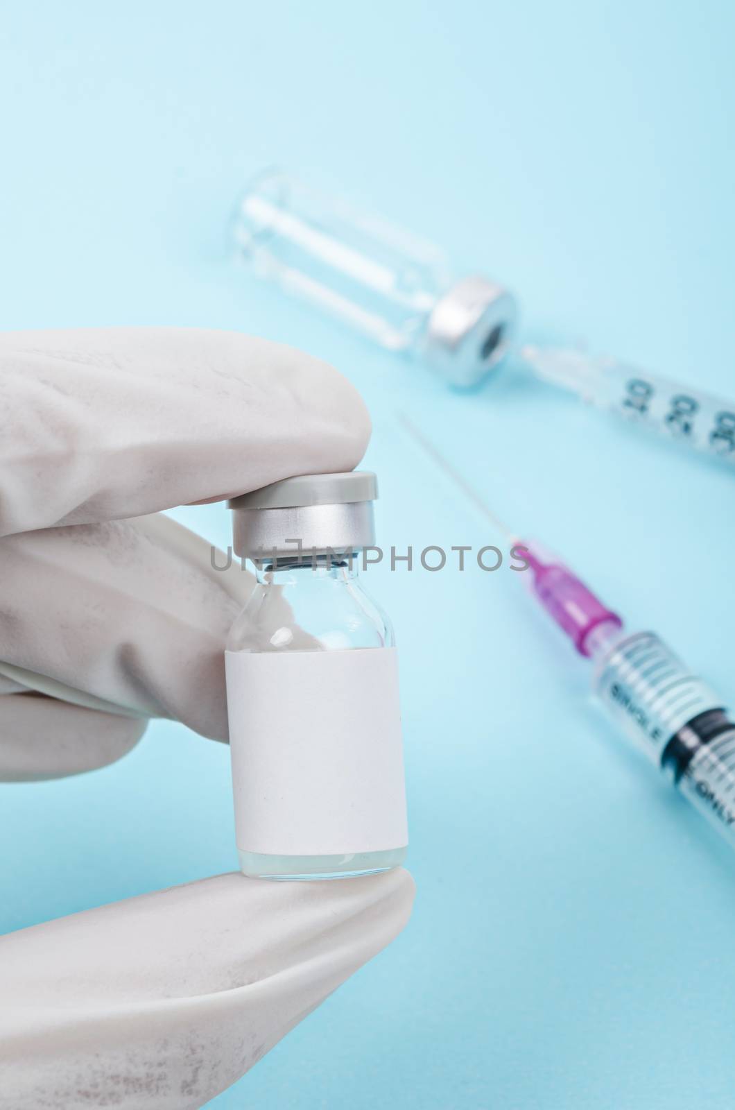 Medicine bottle for injection in hand with white glove. Medical glass vial for vaccination in laboratory, hospital or pharmacy.