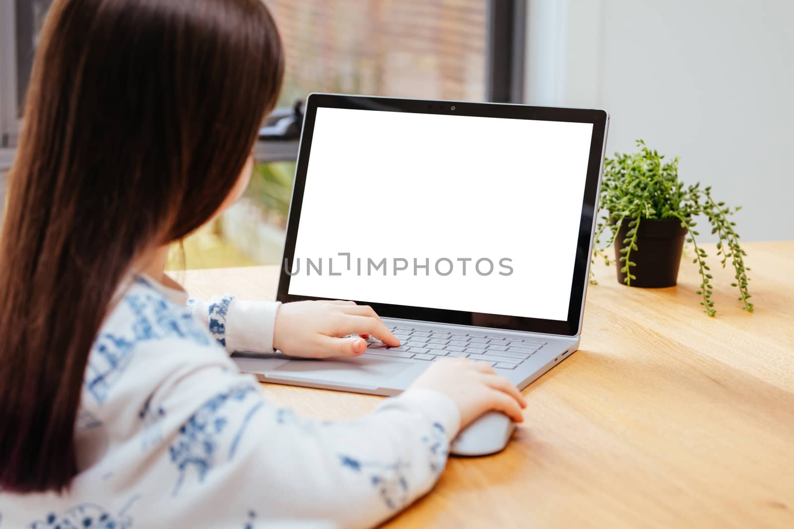 A young female child uses a computer in remote learning for her school work