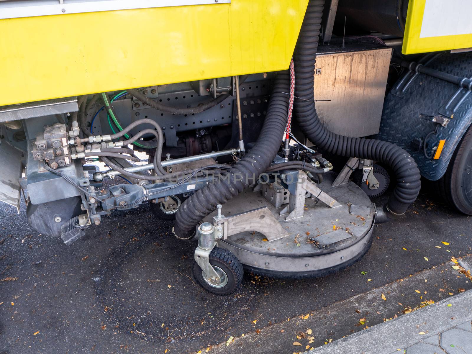 a car for cleaning roads with round brushes on a city street.