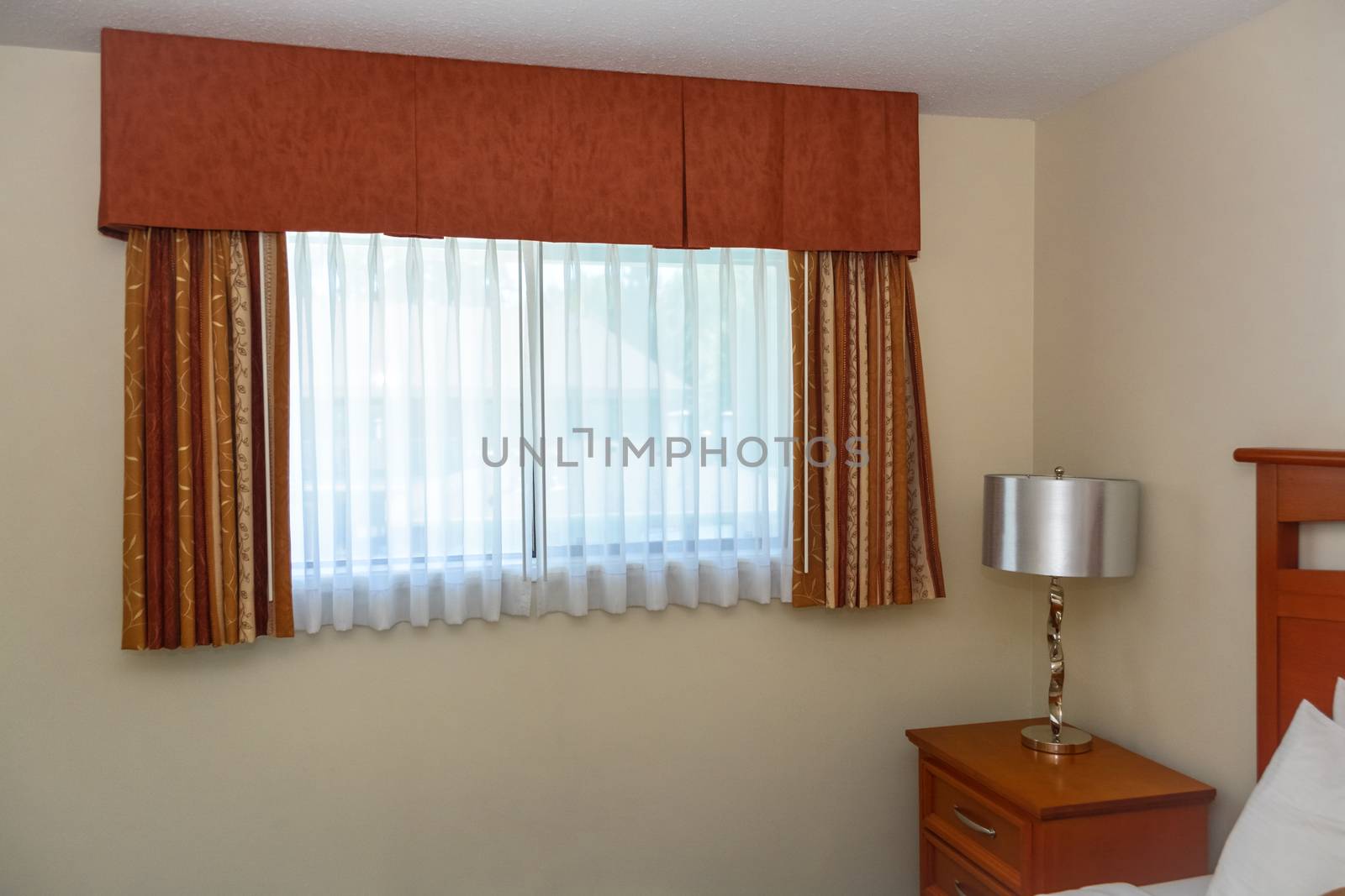 Bedroom window with the curtains and bedside table in the corner of the room