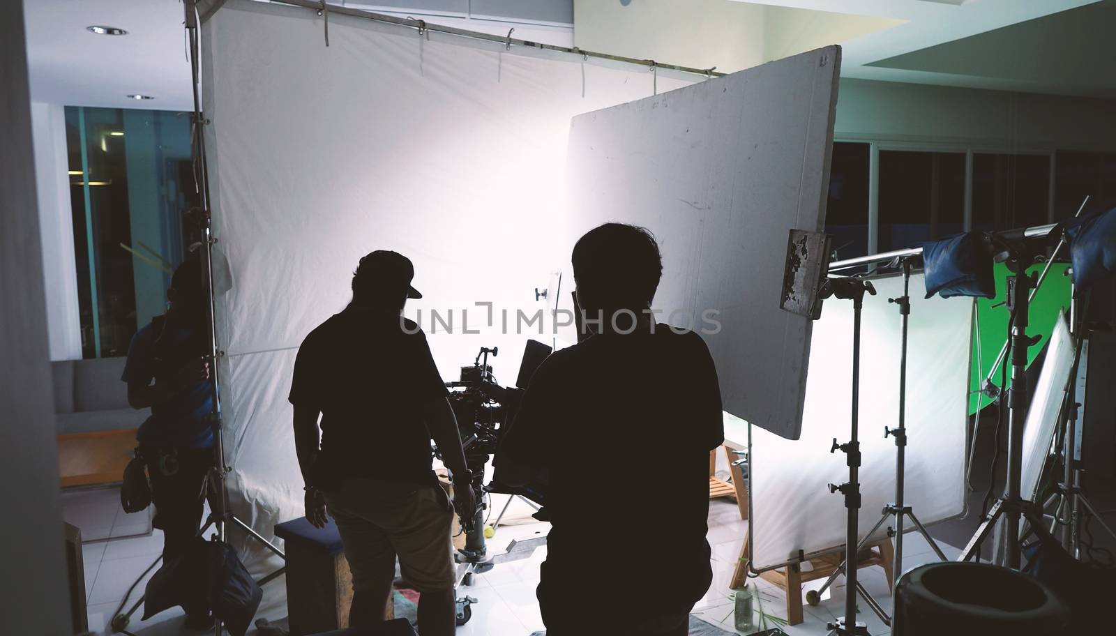 Behind the scenes of shooting video or movie production crew team and silhouette of camera and equipment in studio. 