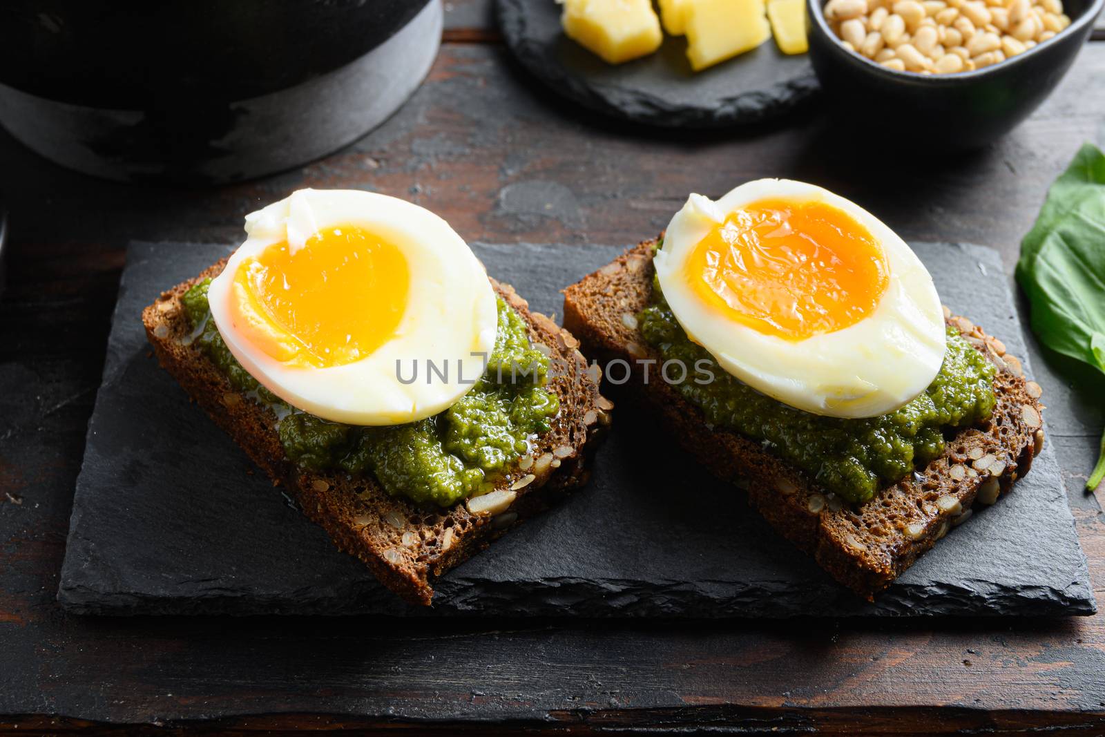 eggs panini bread with pesto and hot sriracha sauce italian breakfast with ingredients green pesto side view close up.