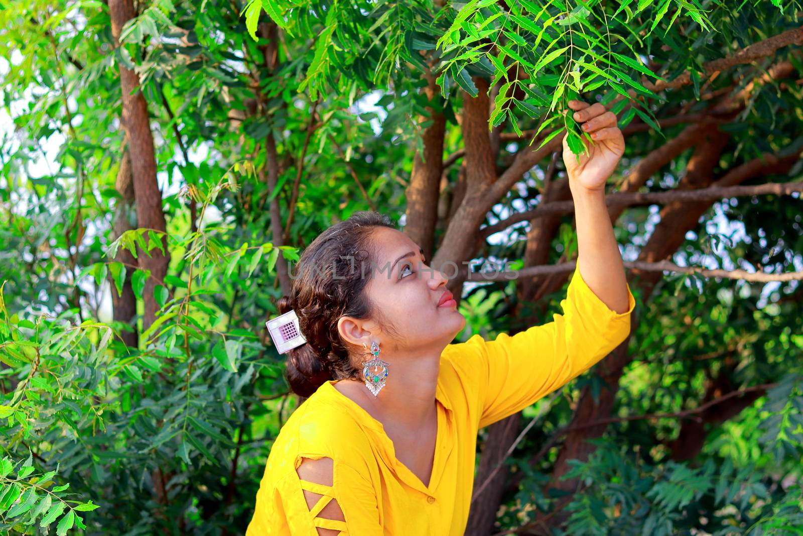 A fashionable Indian model girl touching fresh leaves with her hands by 9500102400