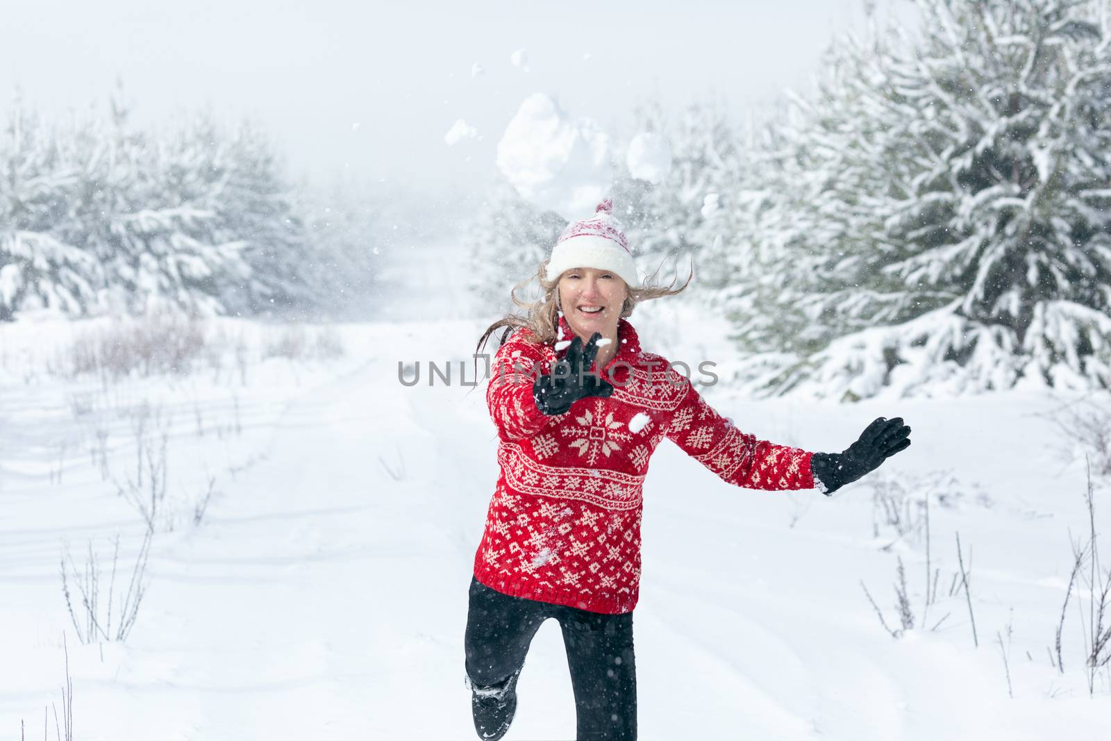 Snowball flying through the air as it leaves womans hands in winter landscape