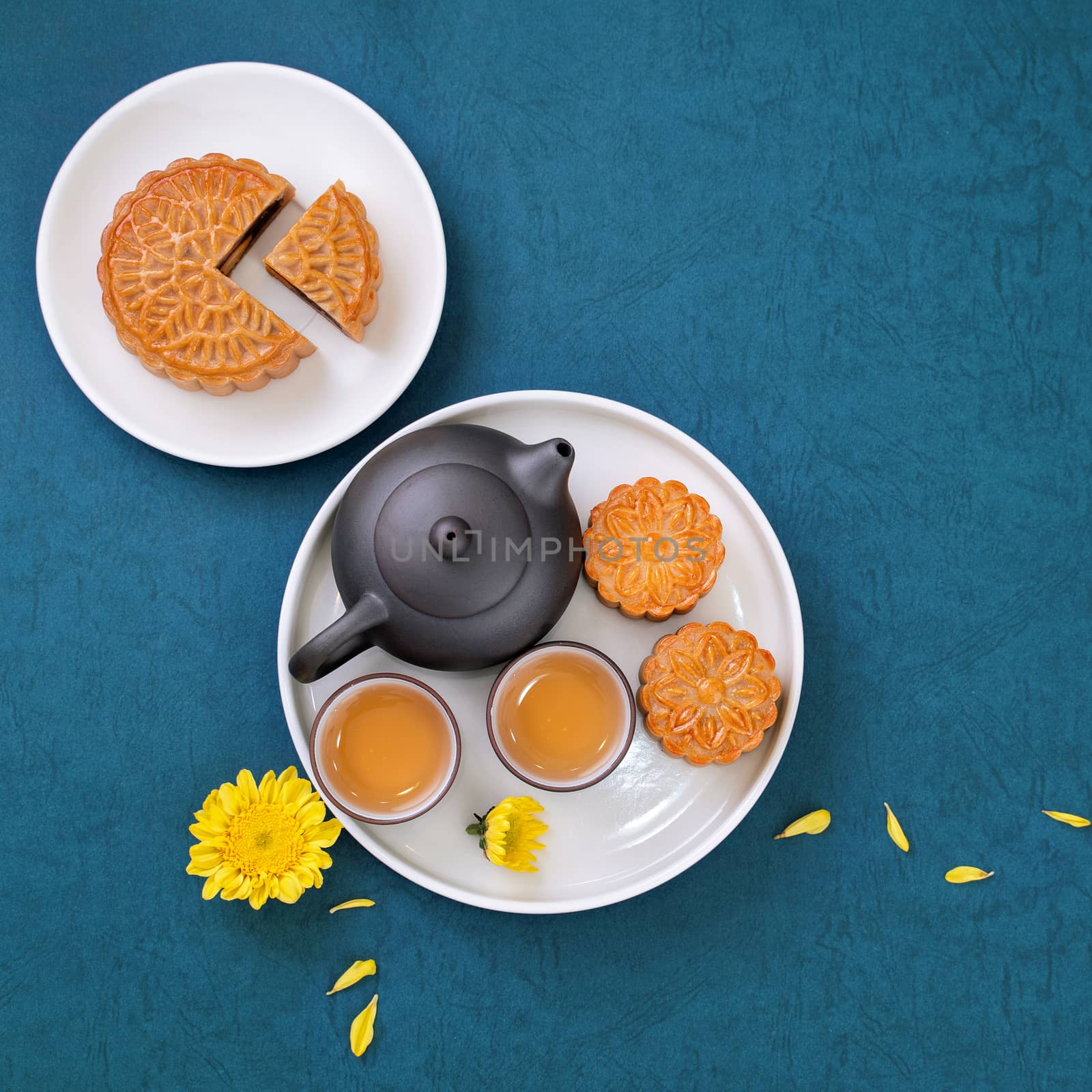 Moon cake for Mid-Autumn Festival, delicious beautiful fresh mooncake on a plate over blue background table, top view, flat lay layout design concept.