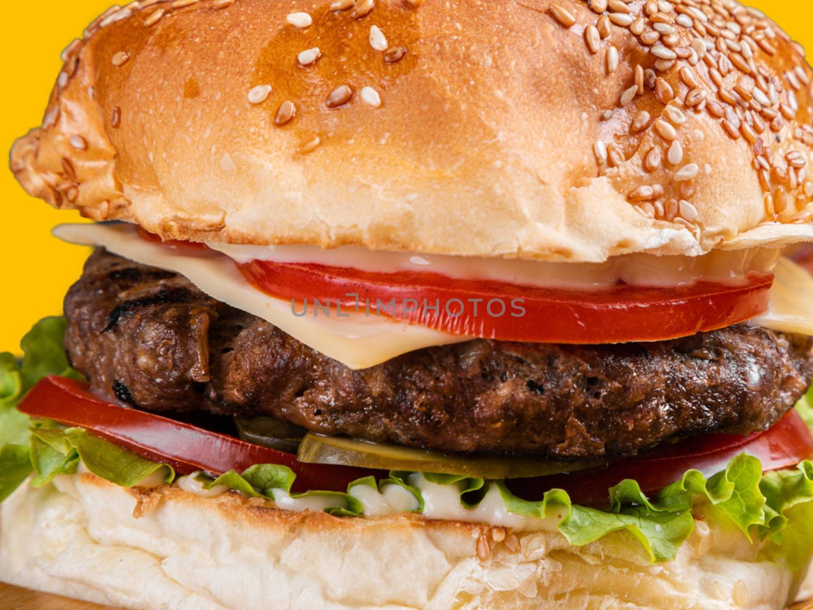 A close up of a delicious hamburger with beef, cheese, and vegetables.