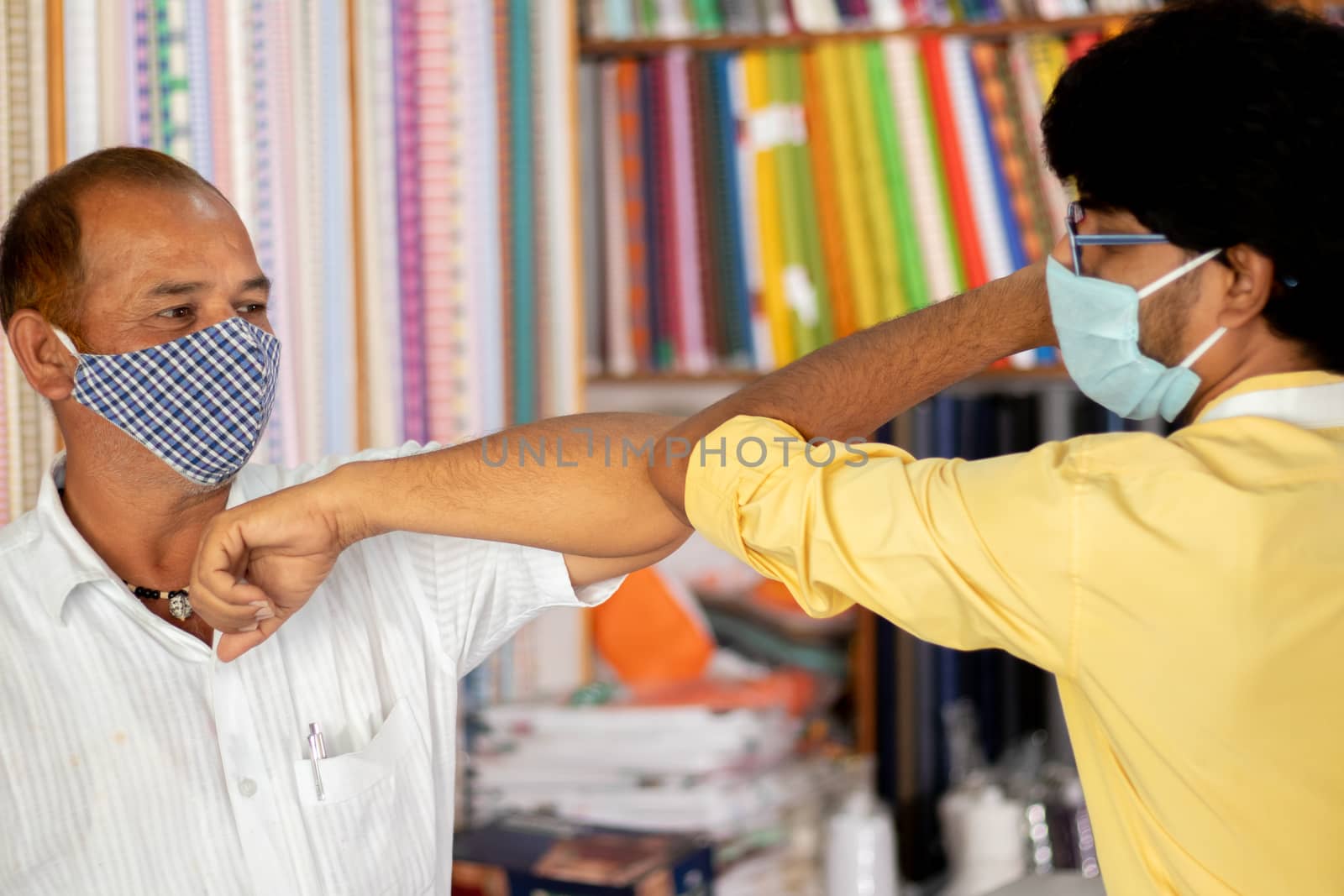Shopkeeper greeting customer with elbow bump at cloth store - concept of people avoiding hand shakes at business places to stop spreading coronavirus or covid-19. by lakshmiprasad.maski@gmai.com