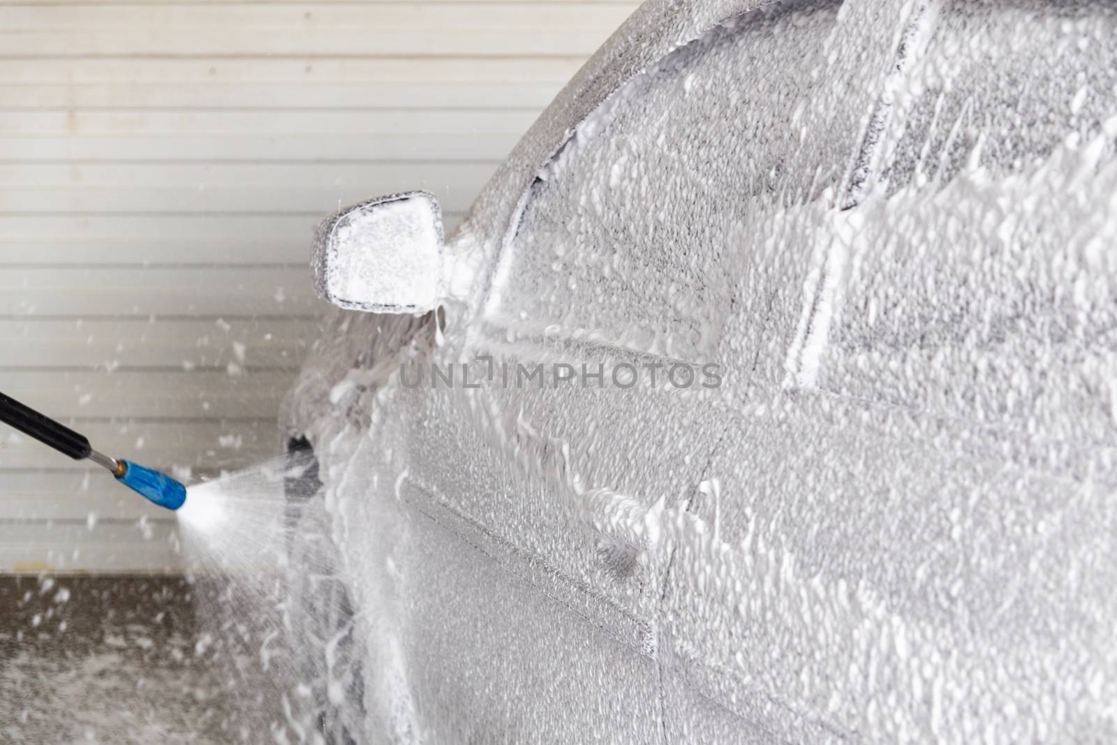 A process of applying soap sud in indoor carwash station - closeup with selective focus and background blur.