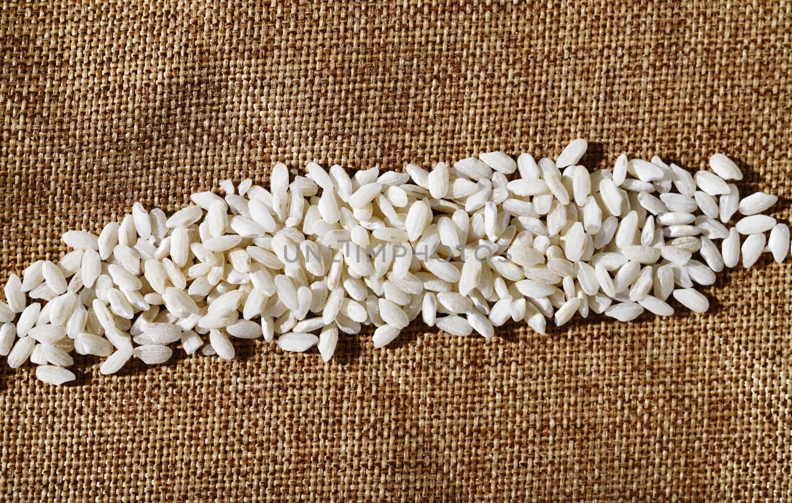White uncooked rice on brown cloth ,regular long grains