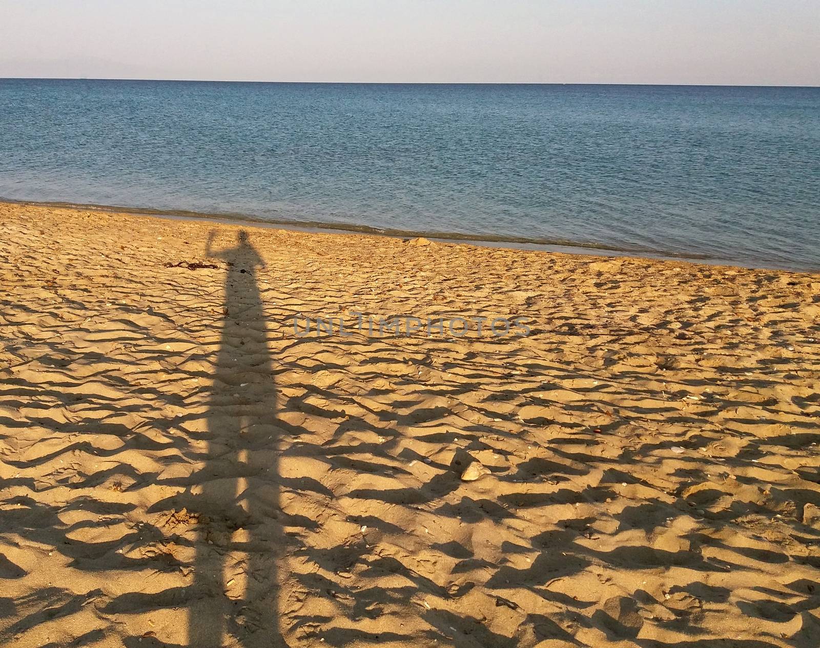 Man's shadow on the mediteranean beach, Greece by Mindru