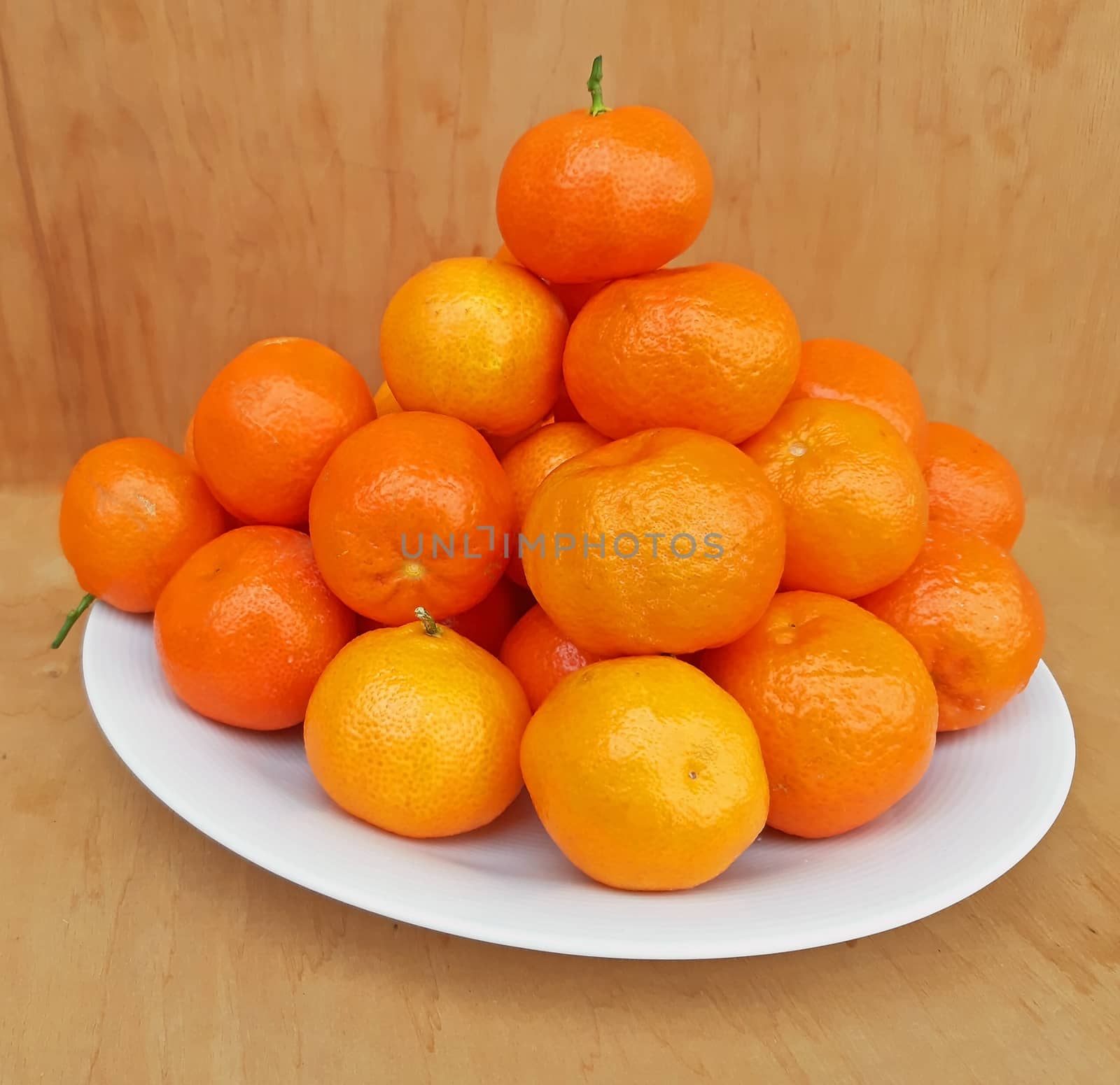 A plate full of clementines, on a wooden background