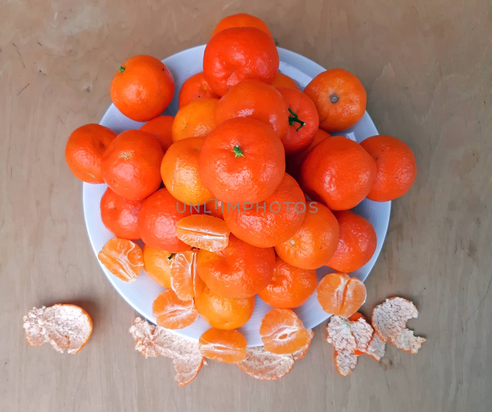 A plate full of clementines, on a wooden background